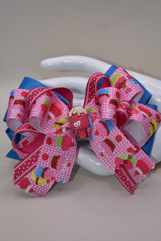 Add a splash of fun with this adorable cupcake ribbon bow, wrapped in bright, multi-colored grosgrain ribbons! 🧁✨ The cutest little charm tops it off, making it perfect for any playful outfit. Finished with a wrapped alligator clip on the back for easy wear and secure hold. 🎀💖 Perfect for adding a sweet touch to your day!