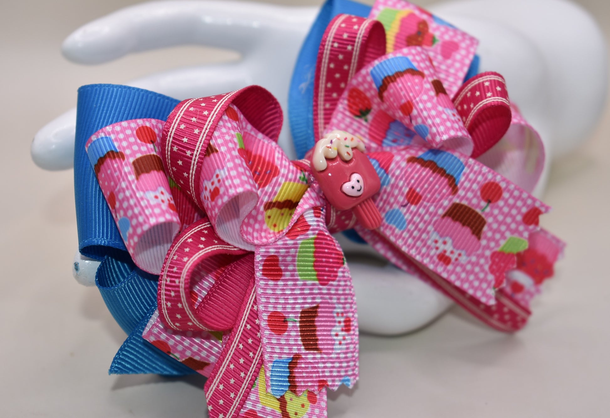 Add a splash of fun with this adorable cupcake ribbon bow, wrapped in bright, multi-colored grosgrain ribbons! 🧁✨ The cutest little charm tops it off, making it perfect for any playful outfit. Finished with a wrapped alligator clip on the back for easy wear and secure hold. 🎀💖 Perfect for adding a sweet touch to your day!