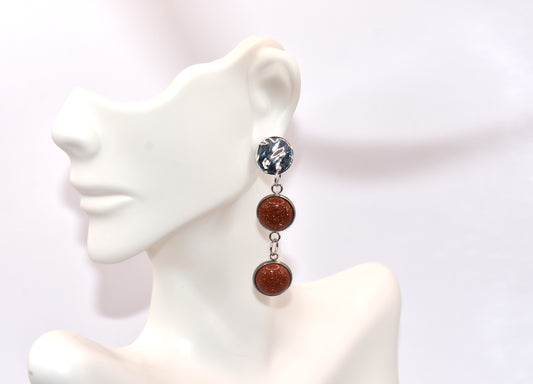 Add a touch of whimsy to any outfit with our Brown Collection earrings! These super comfortable and stylish earrings feature beautiful copper sparkling cabochon stones and hypoallergenic silver posts for sensitive ears. With a versatile neutral color, they'll easily complement any look. Earrings hang 2 inches from the ear for a perfect statement.