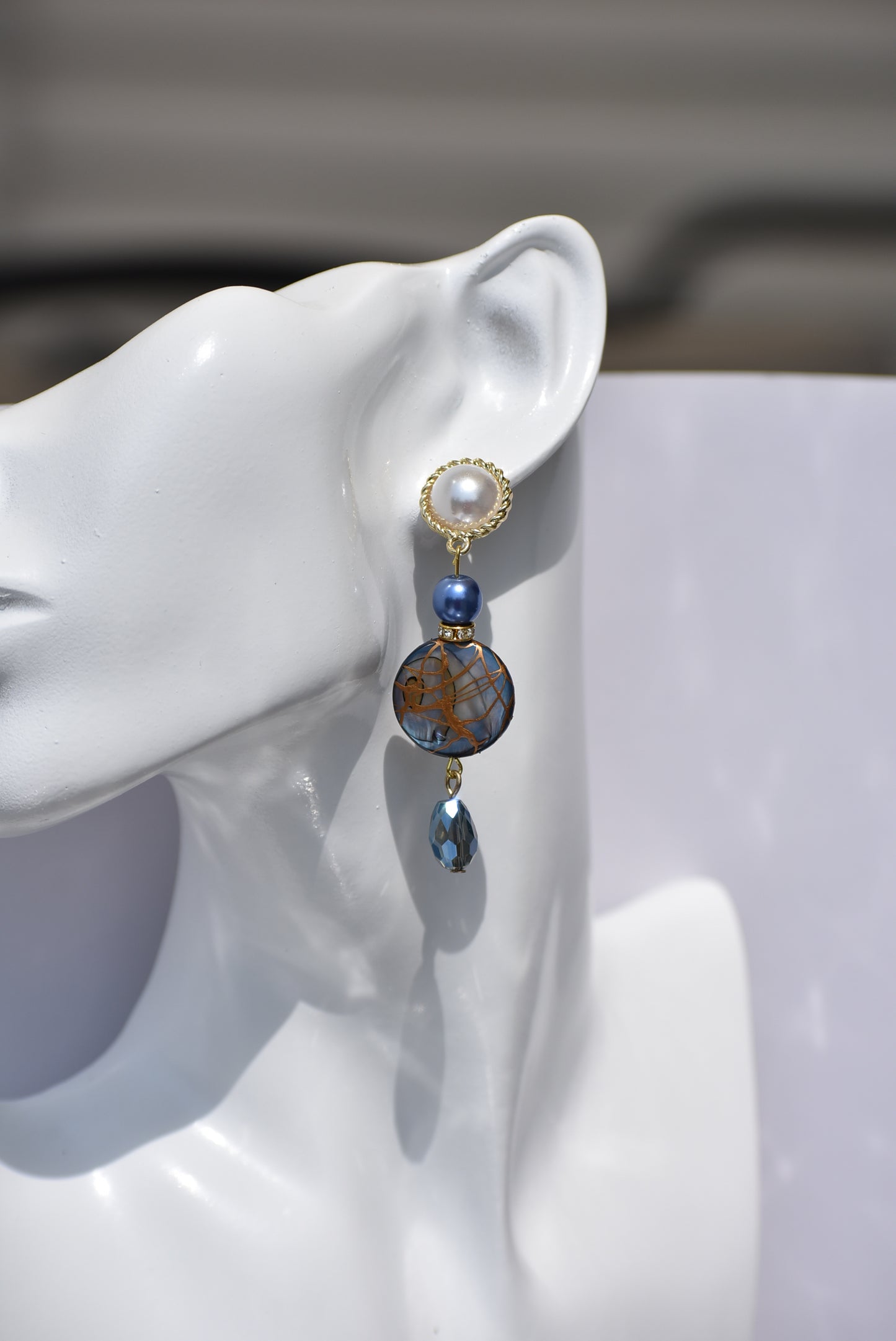  The Blue Collection 22 pearl studs feature a one-of-a-kind design.&nbsp; They are made with beautiful blue pearls and gems and have an eye-catching long hanging shape, perfect for special occasions. Crafted with care and attention to detail, these earrings will stand out.