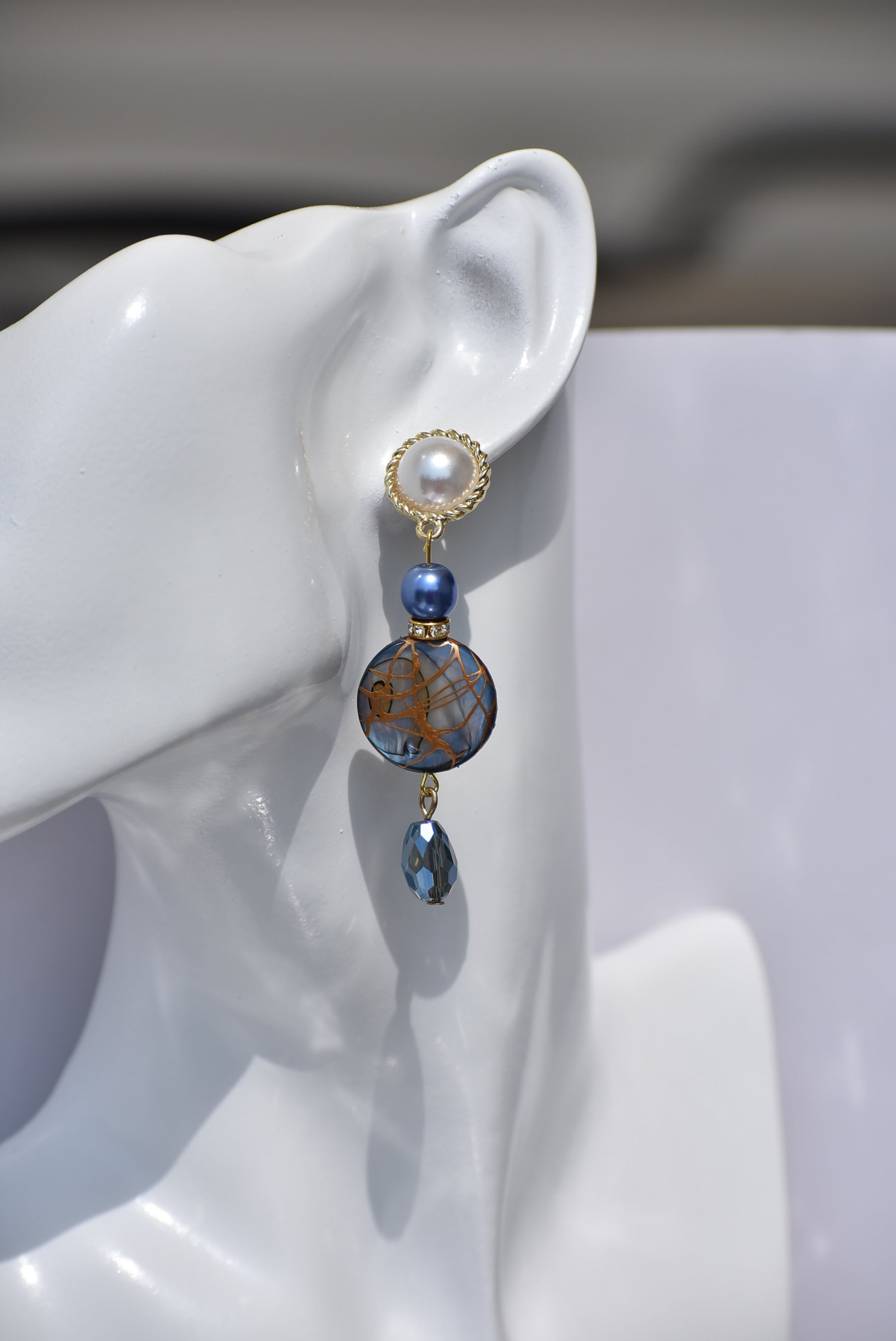 The Blue Collection 22 pearl studs feature a one-of-a-kind design.&nbsp; They are made with beautiful blue pearls and gems and have an eye-catching long hanging shape, perfect for special occasions. Crafted with care and attention to detail, these earrings will stand out.