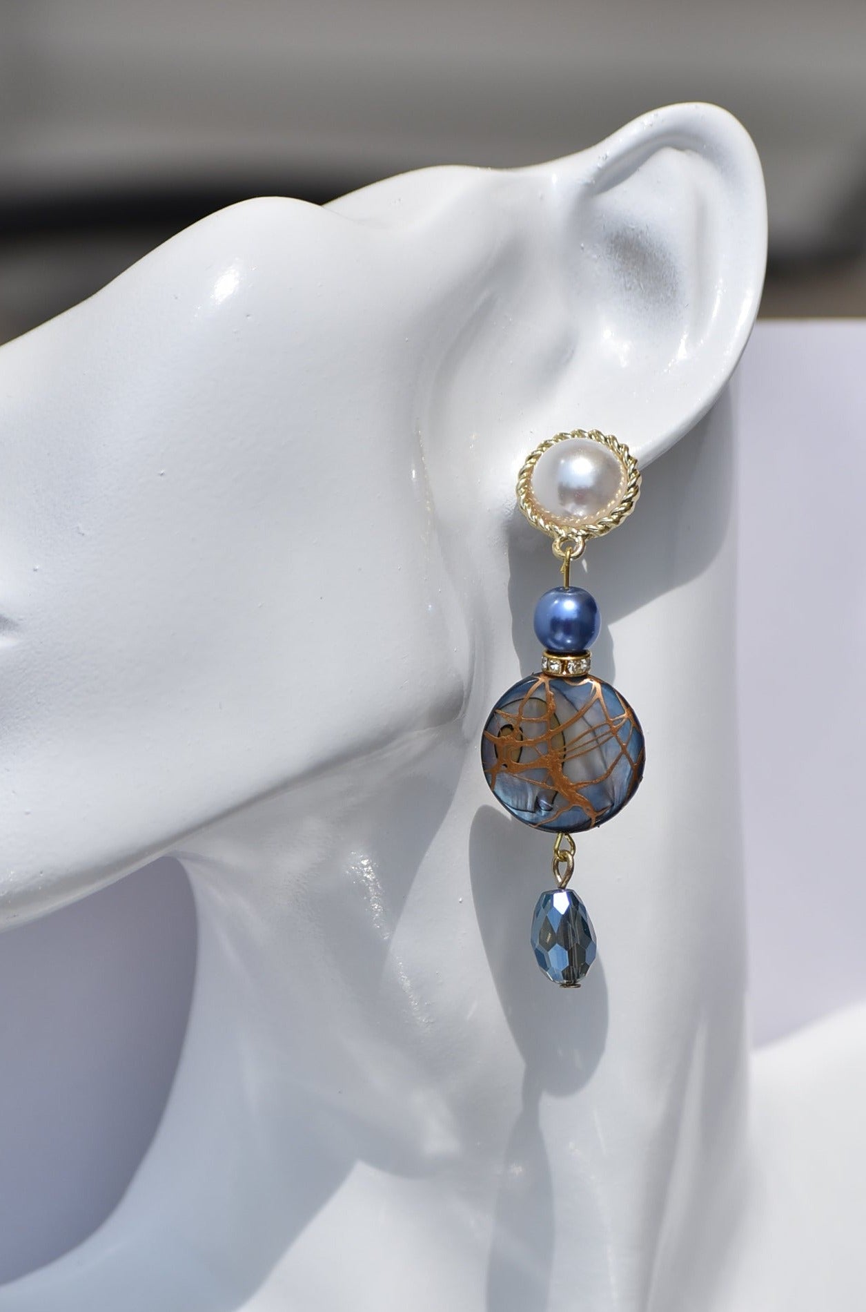 The Blue Collection 22 pearl studs feature a one-of-a-kind design.&nbsp; They are made with beautiful blue pearls and gems and have an eye-catching long hanging shape, perfect for special occasions. Crafted with care and attention to detail, these earrings will stand out.