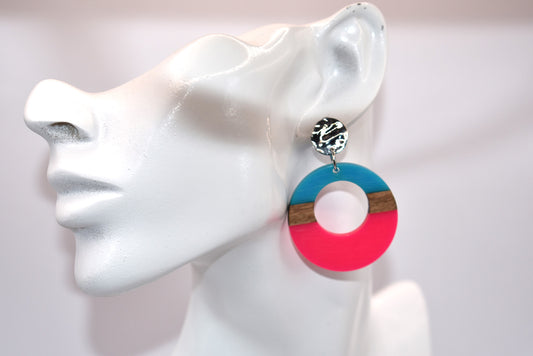 Get ready to soak up the sun with the Pink Collection! This bright pink, aqua, and wood circle hoops will add a pop of color to any outfit. With pretty silver hypoallergenic posts and a lightweight design, these earrings are perfect for your summer wardrobe. Made of wood and resin, they're not only stylish but also sustainable.