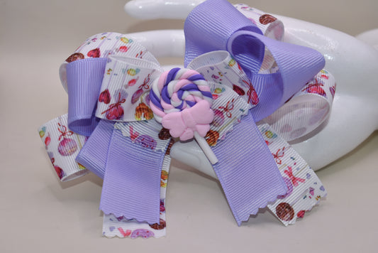 Add a splash of sweetness with Nana's Collection 124! 🍭 This adorable lollipop bow blends soft lavender and pink hues, making it impossible not to love. Perfectly playful and charming, it’s secured with a wrapped alligator clip for easy wear. Get ready to brighten any outfit with this cutie! 💜🎀