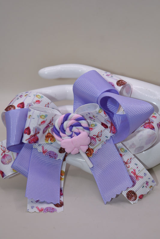 Add a splash of sweetness with Nana's Collection 124! 🍭 This adorable lollipop bow blends soft lavender and pink hues, making it impossible not to love. Perfectly playful and charming, it’s secured with a wrapped alligator clip for easy wear. Get ready to brighten any outfit with this cutie! 💜🎀
