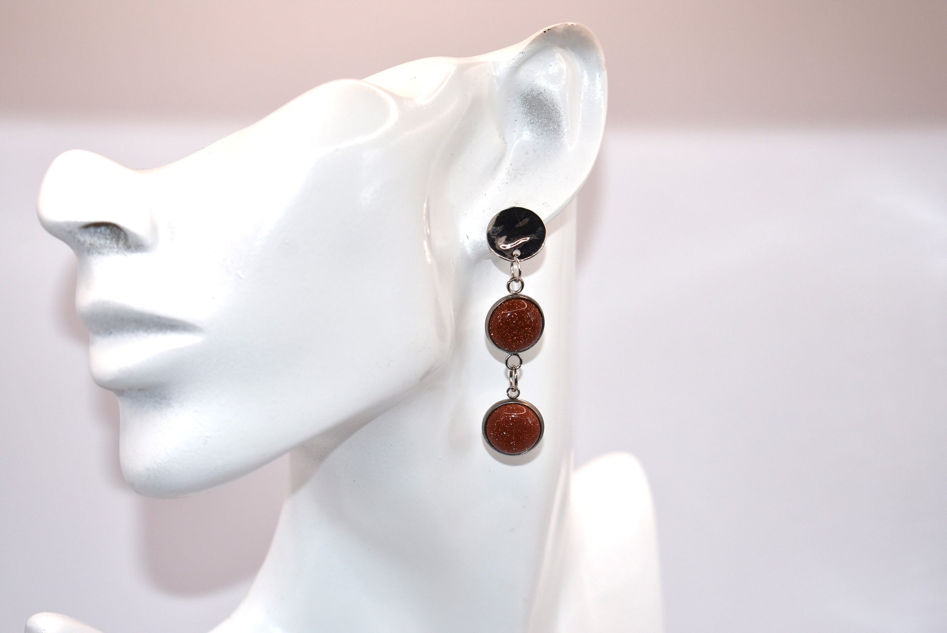 Add a touch of whimsy to any outfit with our Brown Collection earrings! These super comfortable and stylish earrings feature beautiful copper sparkling cabochon stones and hypoallergenic silver posts for sensitive ears. With a versatile neutral color, they'll easily complement any look. Earrings hang 2 inches from the ear for a perfect statement.