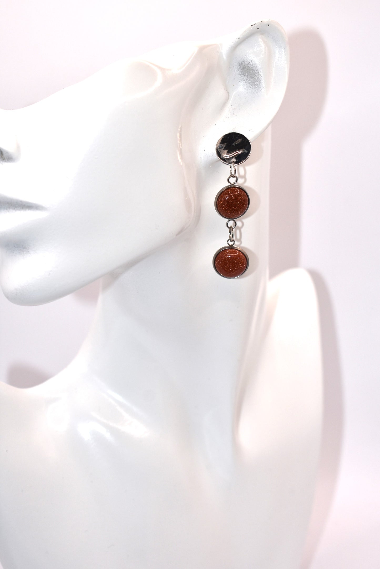 Add a touch of whimsy to any outfit with our Brown Collection earrings! These super comfortable and stylish earrings feature beautiful copper sparkling cabochon stones and hypoallergenic silver posts for sensitive ears. With a versatile neutral color, they'll easily complement any look. Earrings hang 2 inches from the ear for a perfect statement.