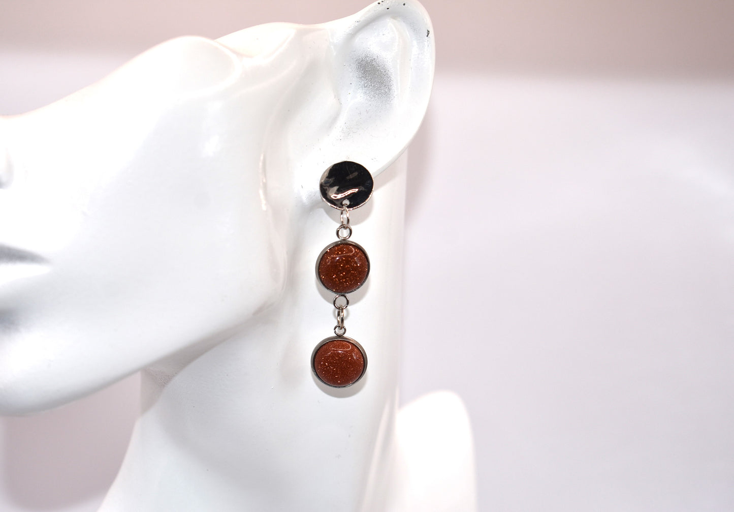 Add a touch of whimsy to any outfit with our Brown Collection earrings! These super comfortable and stylish earrings feature beautiful copper sparkling cabochon stones and hypoallergenic silver posts for sensitive ears. With a versatile neutral color, they'll easily complement any look. Earrings hang 2 inches from the ear for a perfect statement.