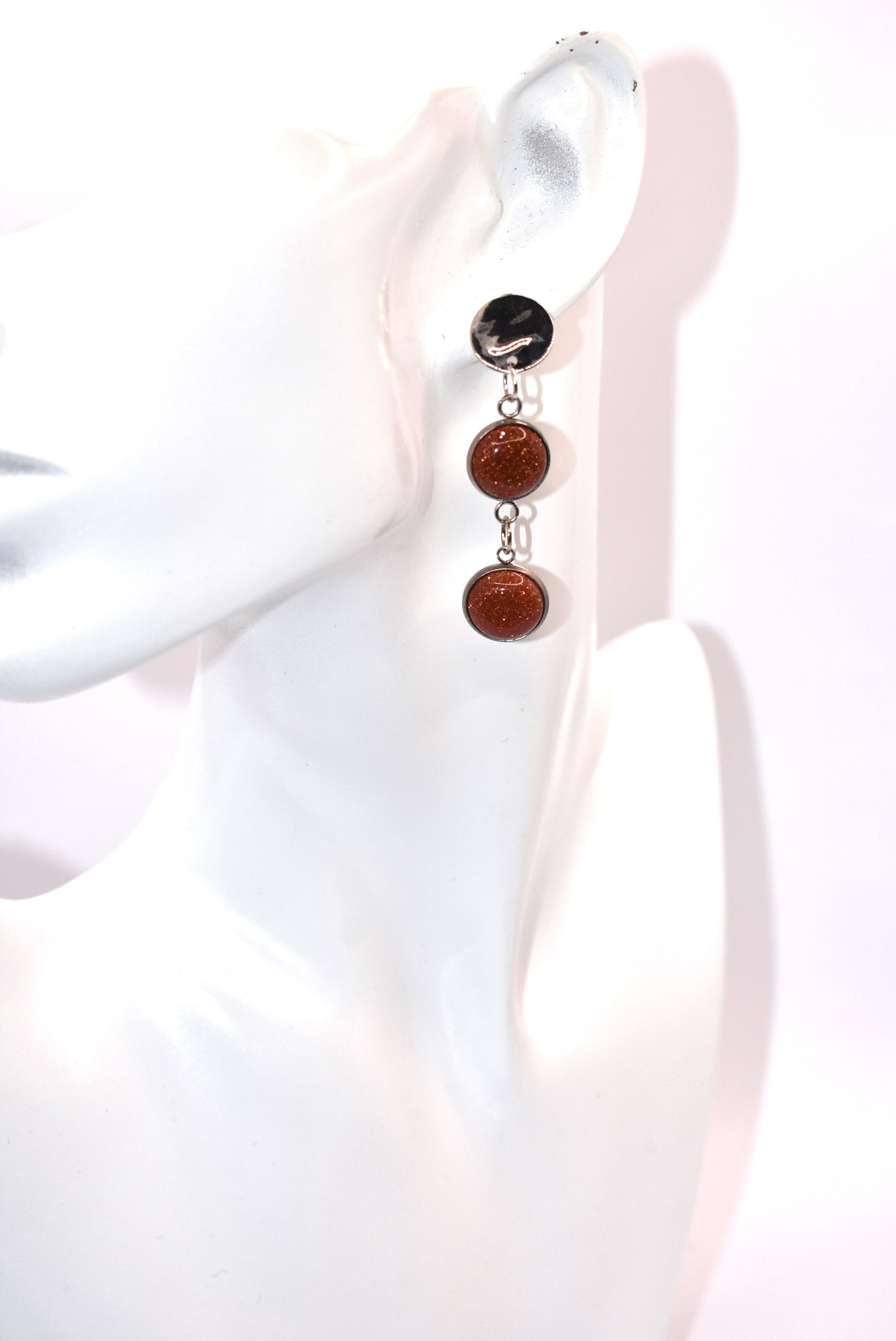 Add a touch of whimsy to any outfit with our Brown Collection earrings! These super comfortable and stylish earrings feature beautiful copper sparkling cabochon stones and hypoallergenic silver posts for sensitive ears. With a versatile neutral color, they'll easily complement any look. Earrings hang 2 inches from the ear for a perfect statement.