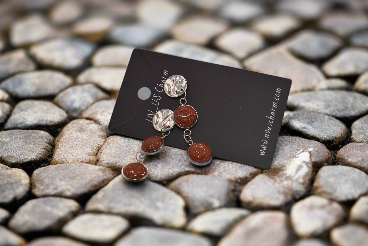 Add a touch of whimsy to any outfit with our Brown Collection earrings! These super comfortable and stylish earrings feature beautiful copper sparkling cabochon stones and hypoallergenic silver posts for sensitive ears. With a versatile neutral color, they'll easily complement any look. Earrings hang 2 inches from the ear for a perfect statement.