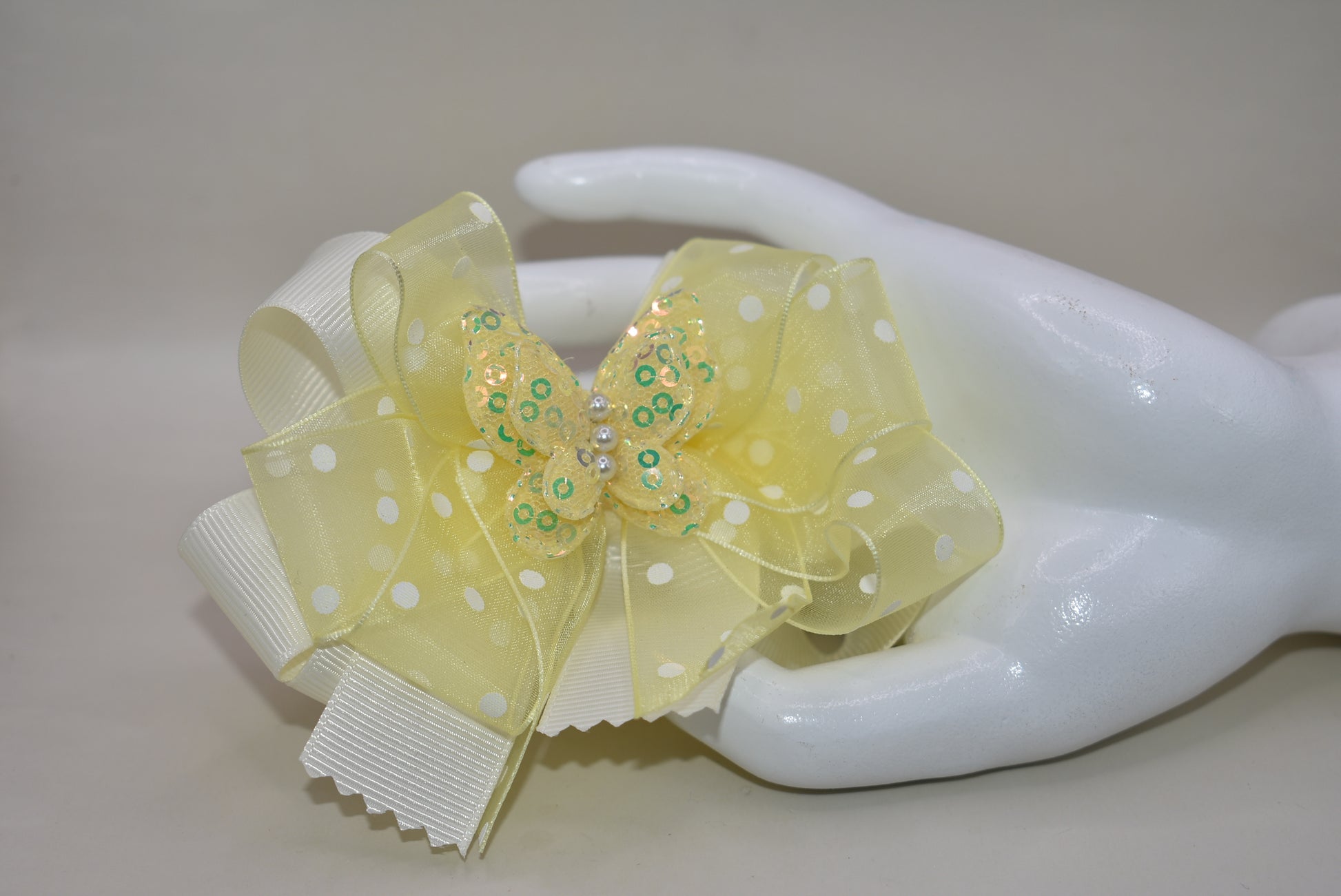 Add a splash of sunshine with this adorable bow from Nana's Collection! 🌼 Soft baby yellow grosgrain and delicate organza ribbons tie together a playful polka dot bow, topped with a sparkly butterfly 🦋. Secured with a wrapped alligator clip, it stays put for all-day fun. Perfect for brightening any outfit with a touch of charm and sparkle! ✨