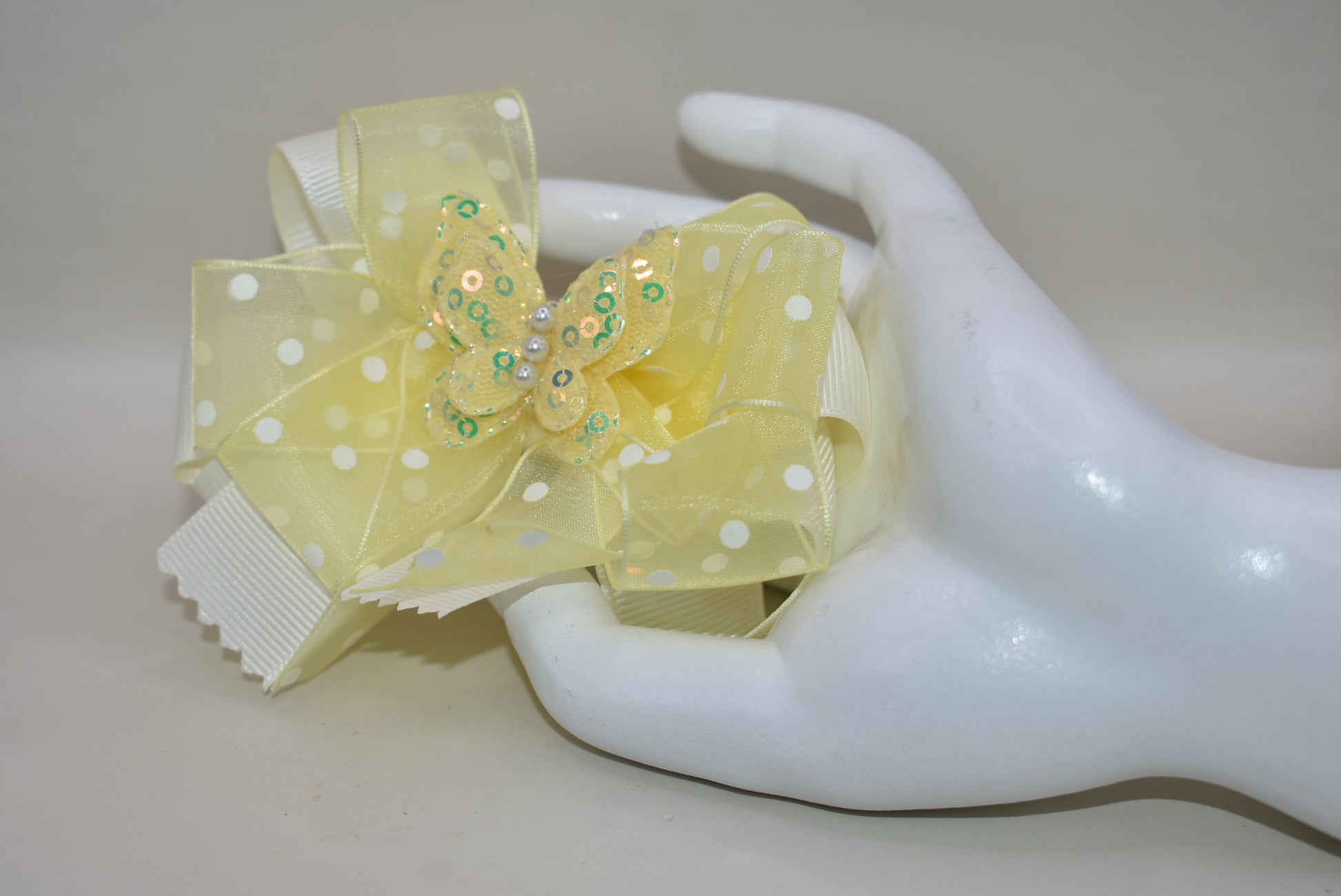 Add a splash of sunshine with this adorable bow from Nana's Collection! 🌼 Soft baby yellow grosgrain and delicate organza ribbons tie together a playful polka dot bow, topped with a sparkly butterfly 🦋. Secured with a wrapped alligator clip, it stays put for all-day fun. Perfect for brightening any outfit with a touch of charm and sparkle! ✨