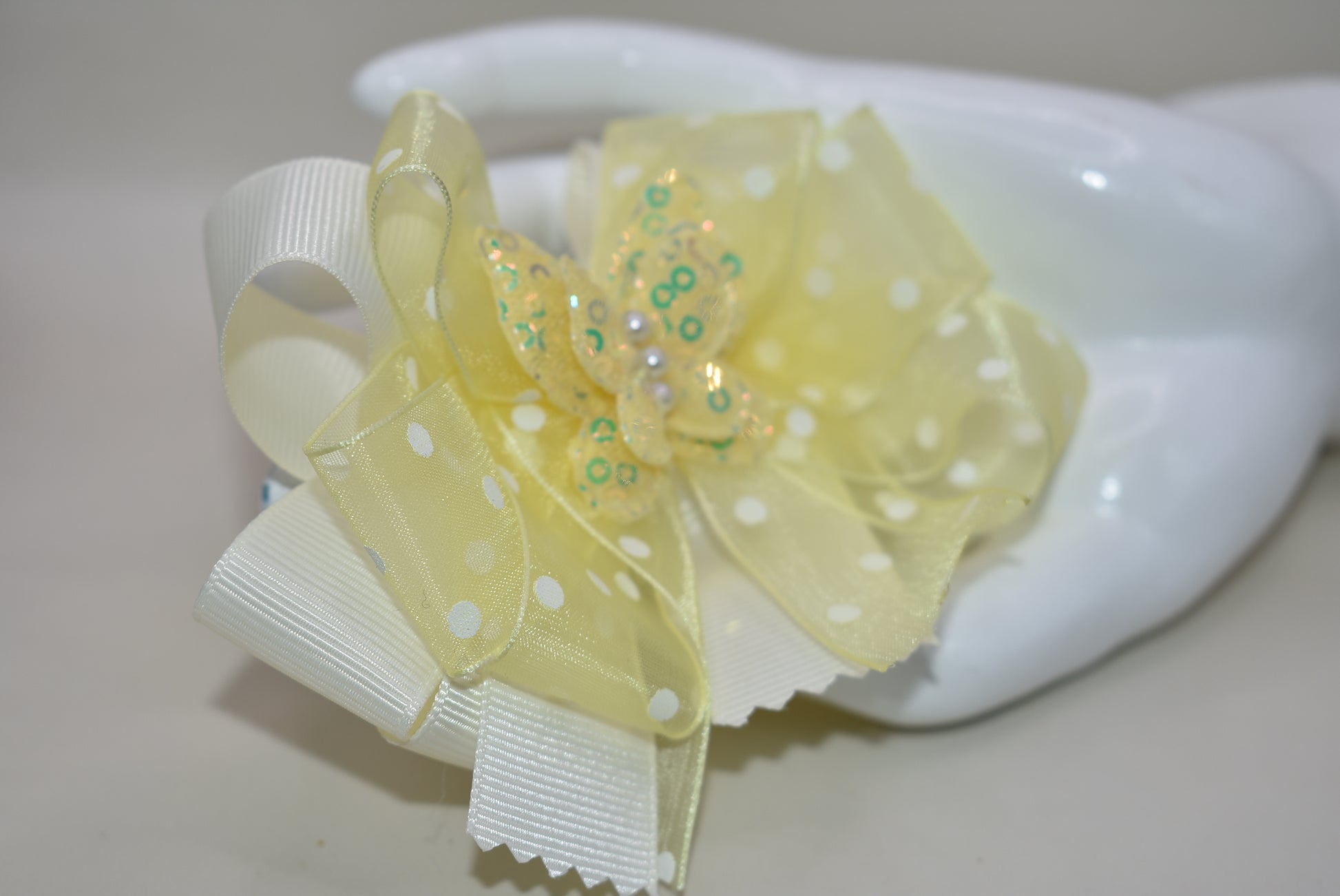 Add a splash of sunshine with this adorable bow from Nana's Collection! 🌼 Soft baby yellow grosgrain and delicate organza ribbons tie together a playful polka dot bow, topped with a sparkly butterfly 🦋. Secured with a wrapped alligator clip, it stays put for all-day fun. Perfect for brightening any outfit with a touch of charm and sparkle! ✨