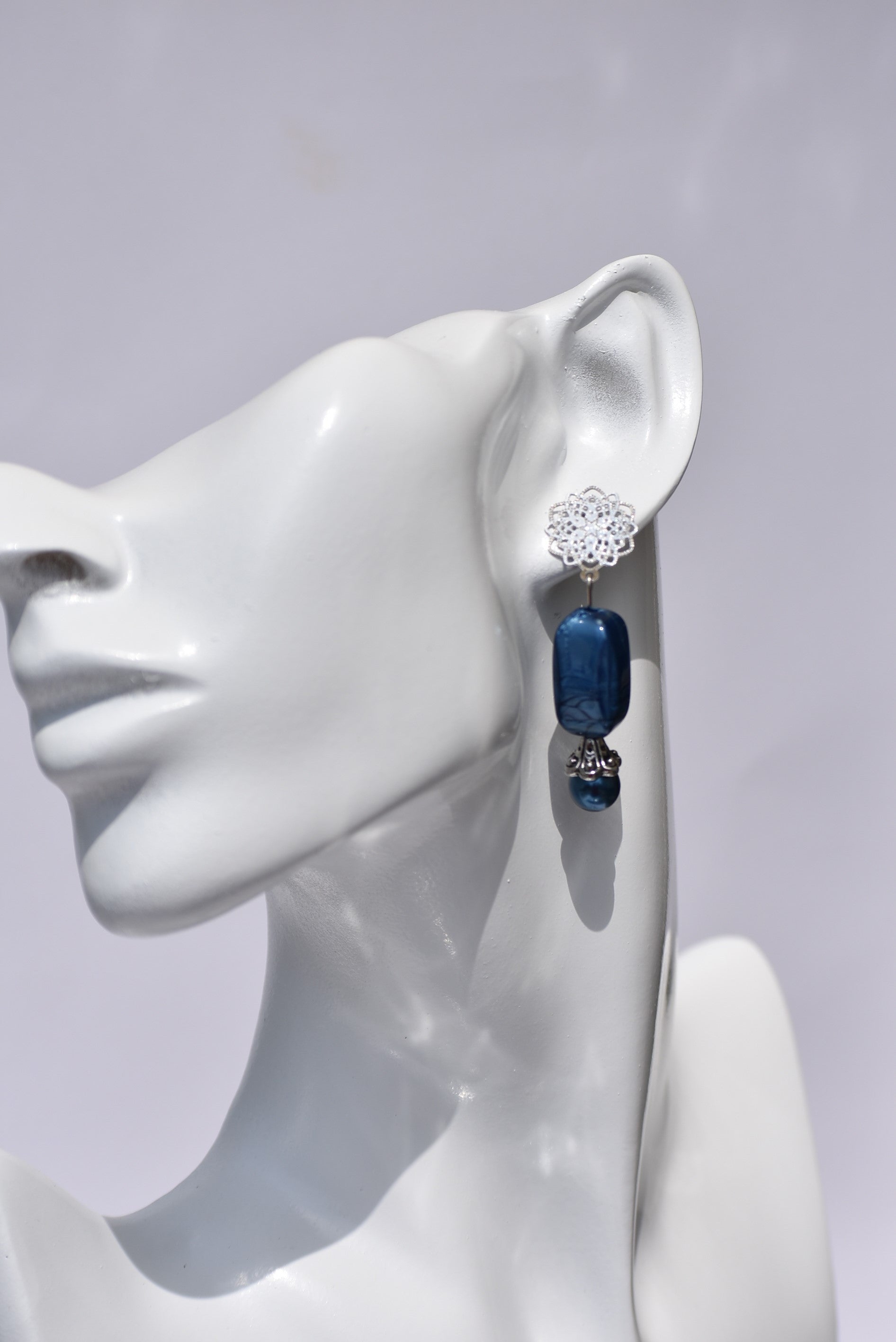 The Blue Collection 12 earrings are a unique and timeless piece crafted with beautiful sapphire blue pearl and beads, coupled with a silver filigree post. With their elegant and classic design, you'll be sure to turn heads.