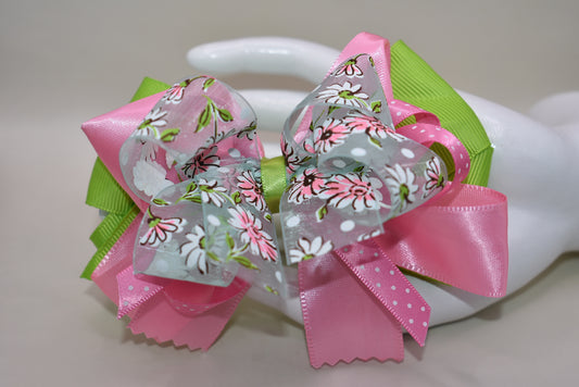 Add a splash of charm with Nana's Collection 106! 🌸 Delightful layers of silk, grosgrain, and organza ribbons in soft pinks and greens create a sweet, playful look. The delicate flower design on the organza ribbon adds an extra touch of whimsy 🌷. Finished with a wrapped alligator clip, it stays put all day for endless fun! 🎀✨
