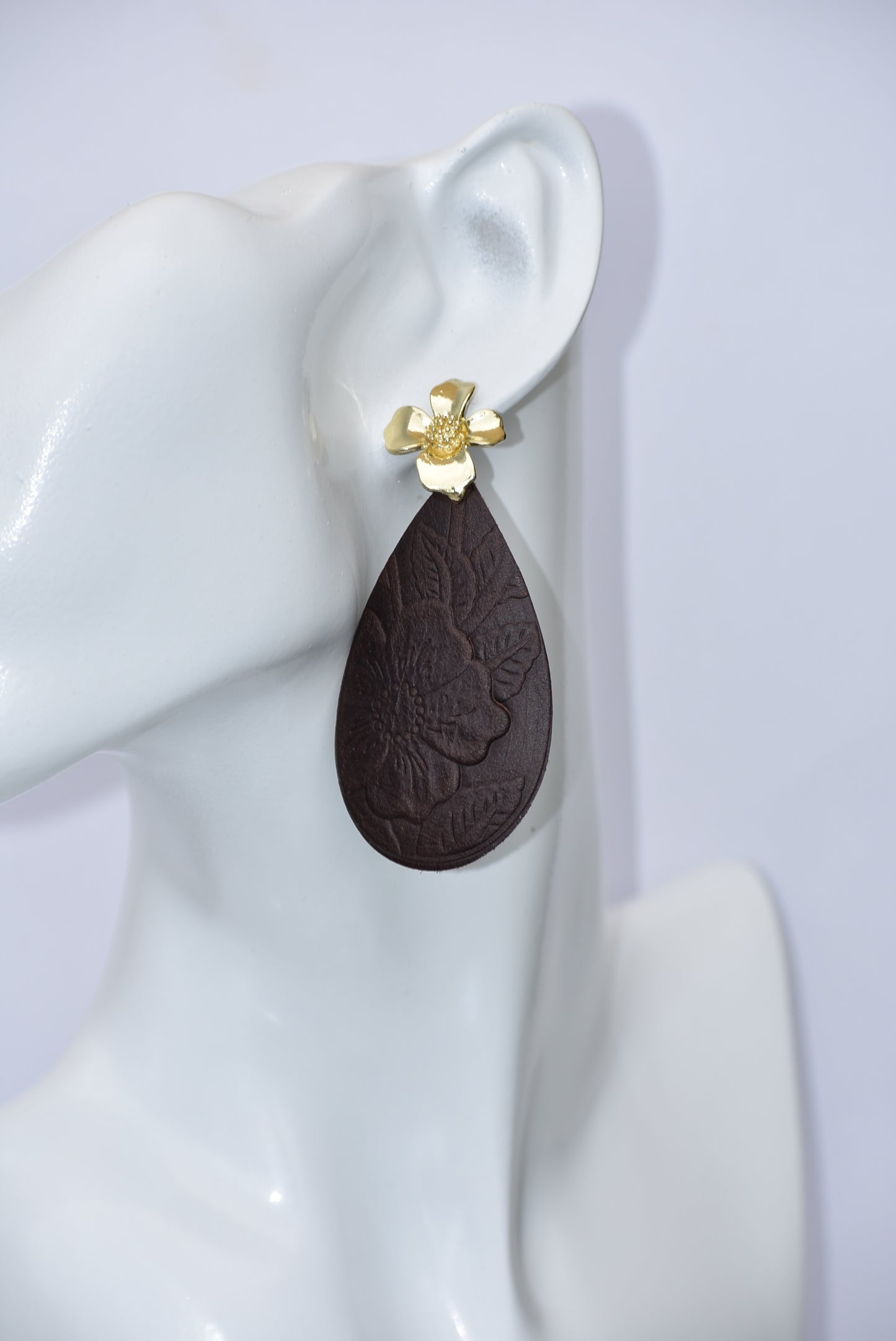 Experience the beauty of the Brown Collection. Crafted with dark brown flower-pressed faux leather in a unique teardrop shape. The elegant gold flower post earrings add a touch of glamour. Hypoallergenic and infused with Hawaiian flair, these earrings are perfect for any occasion.