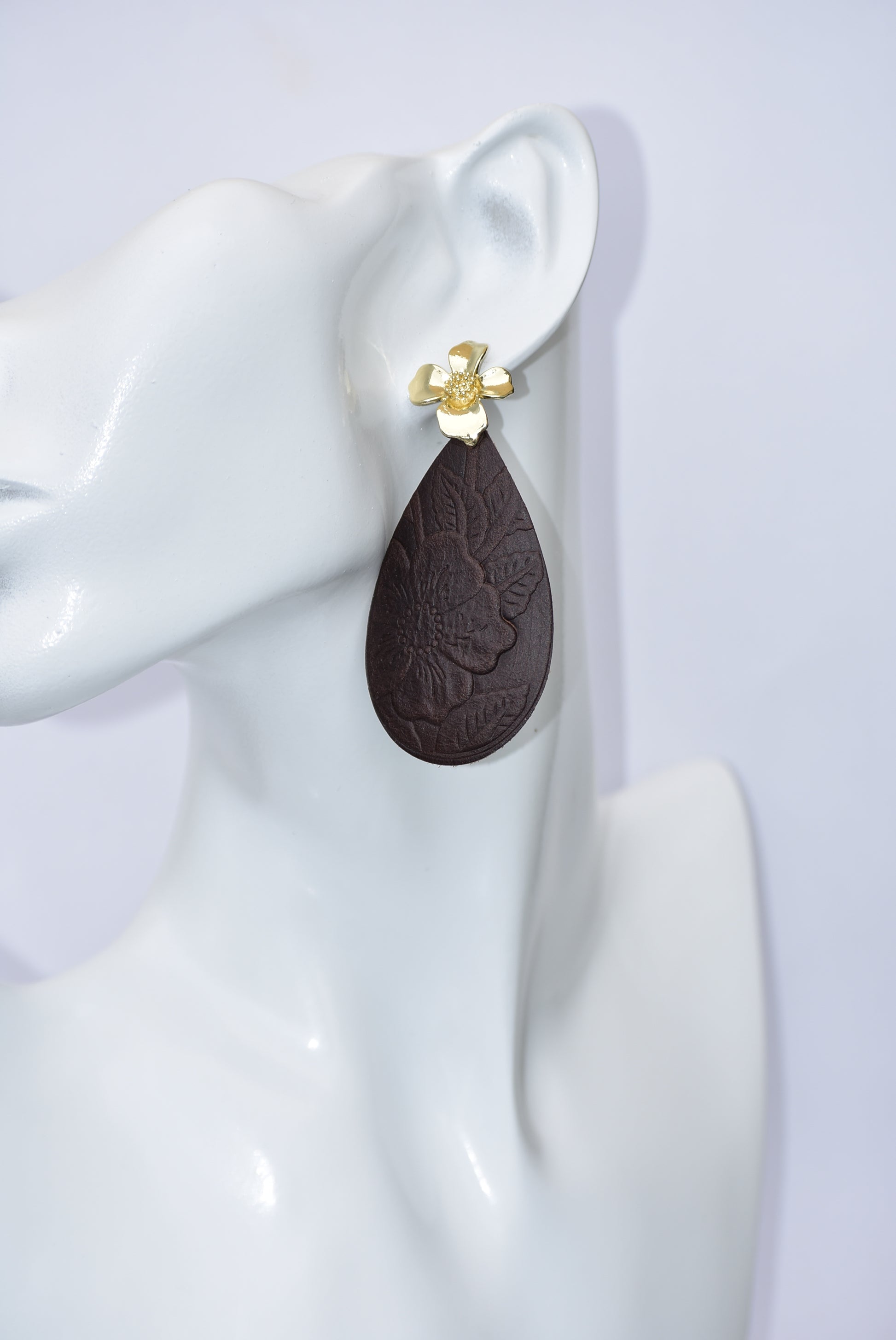 Experience the beauty of the Brown Collection. Crafted with dark brown flower-pressed faux leather in a unique teardrop shape. The elegant gold flower post earrings add a touch of glamour. Hypoallergenic and infused with Hawaiian flair, these earrings are perfect for any occasion.