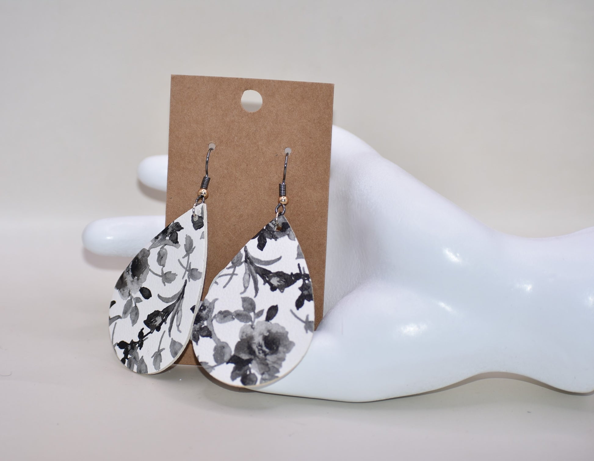 Add a touch of playfulness to any outfit with our Key West Collection earrings! These unique faux leather teardrop earrings feature a pretty black and white flower design and a quirky black hook with a gold ball. Comfortable yet stylish, they're perfect for dressing up or down. 😉