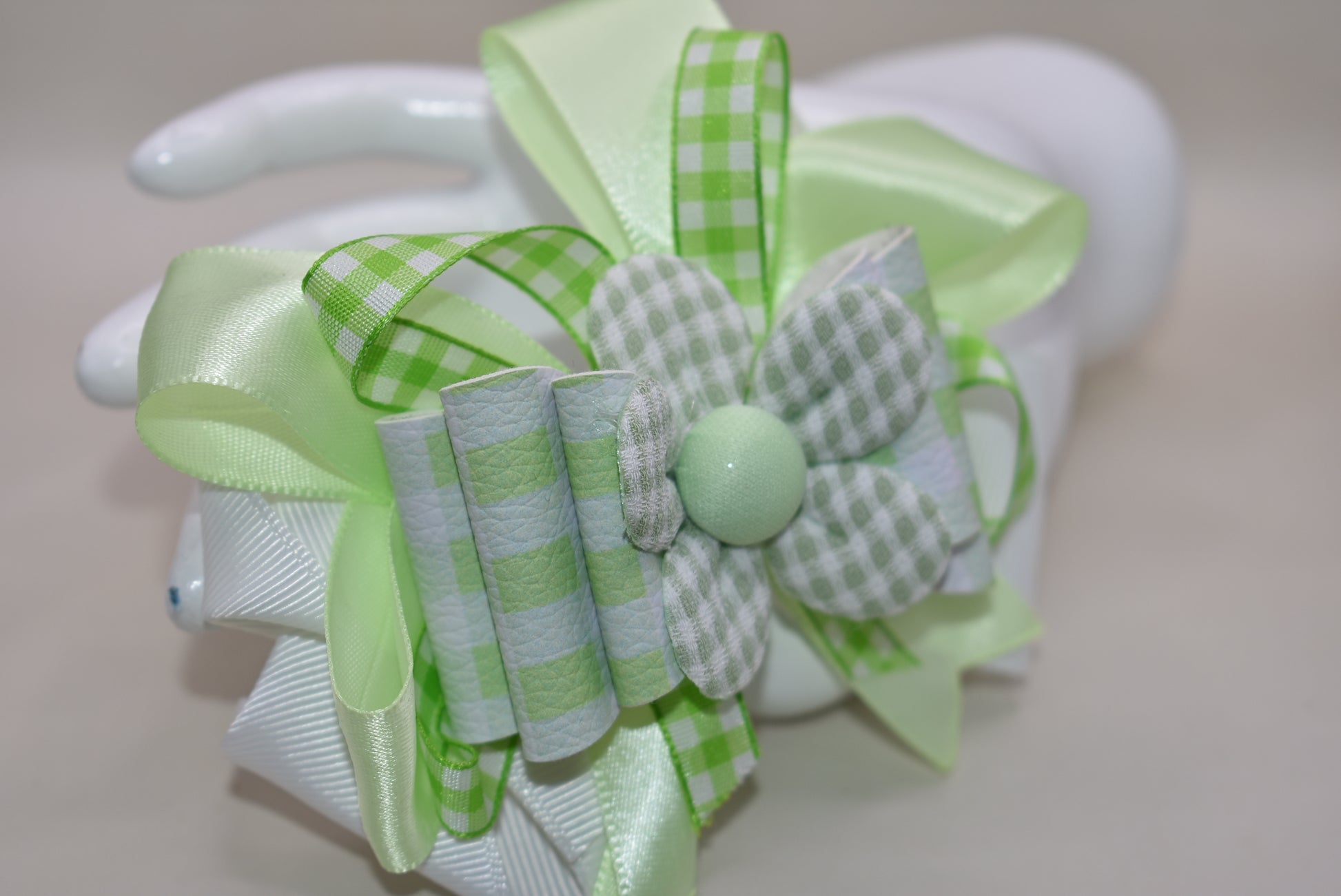 Add a splash of fun with this playful green and white checkered ribbon bow from Nana's Collection. Its charming pattern brings a lively touch to any outfit, while the covered alligator clip ensures it stays put comfortably all day. Perfect for adding a cute, cheerful accent wherever you go!