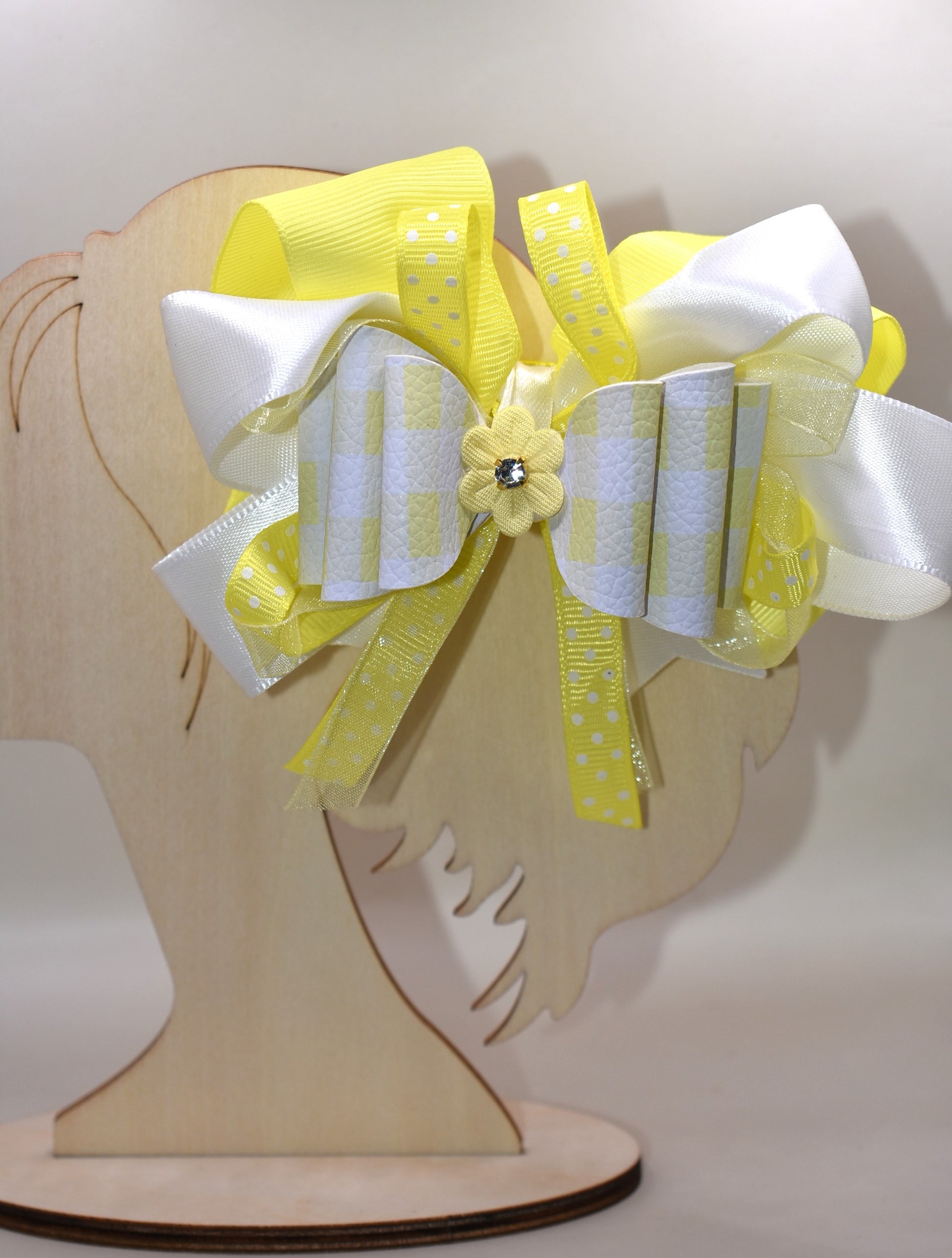 Add a splash of sunshine to your look with this playful hair clip from Nana's Collection 166. Featuring a cheerful mix of yellow and white ribbons accented with charming polka dots, it’s topped with a cute yellow flower and sparkling crystal for a touch of sparkle. The wrapped alligator clip ensures a secure hold, making it perfect for brightening any hairstyle with a fun, whimsical flair.