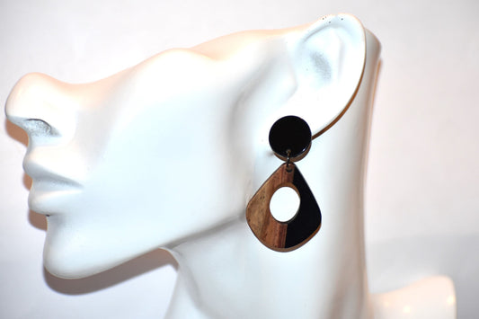 Elevate your wardrobe with our Black Collection! These stunning oval earrings, held by black round posts, will perfectly complement any outfit. Whether dressing up or down, these black resin and wood beauties are sure to make a statement. A must-have for any fashionista!