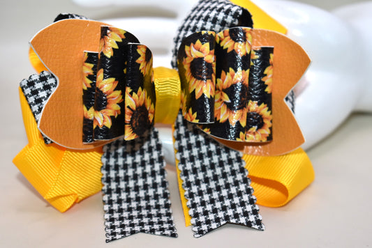 Brighten any outfit with this playful hair clip featuring a charming sunflower motif and layers of pretty ribbon. The black and white checkered ribbon adds a fun touch, while the wrapped alligator clip ensures a secure fit all day long. Perfect for adding a splash of sunshine wherever you go! 🌻🎀🖤🤍