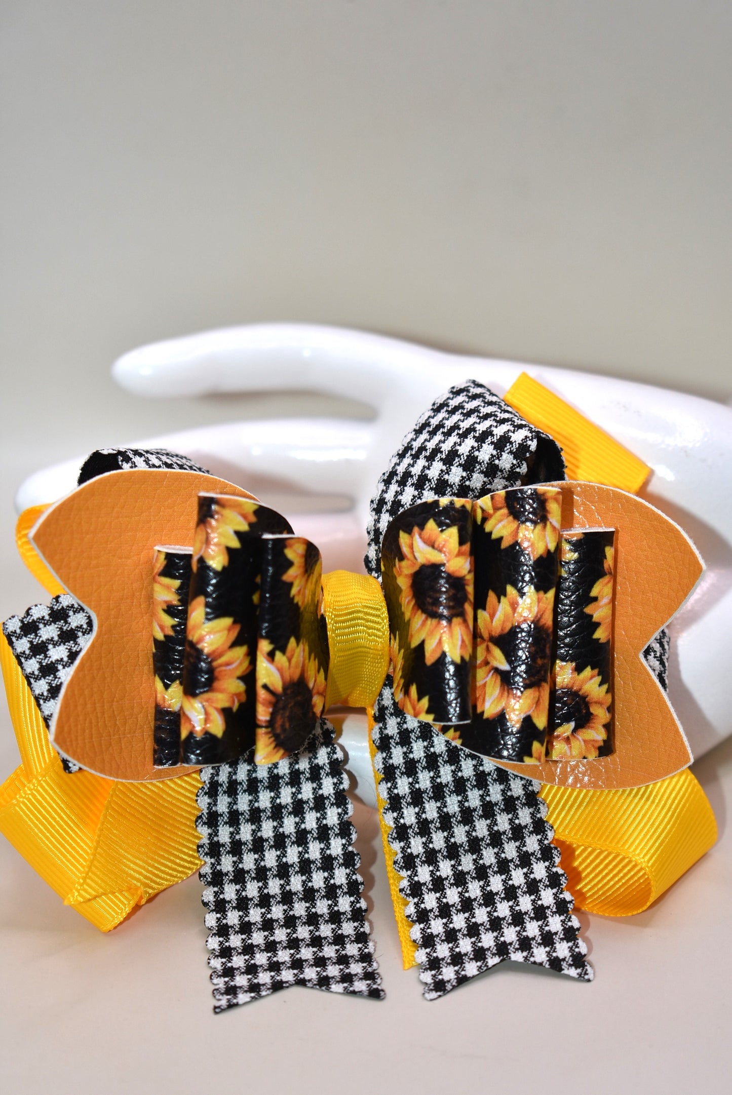 Brighten any outfit with this playful hair clip featuring a charming sunflower motif and layers of pretty ribbon. The black and white checkered ribbon adds a fun touch, while the wrapped alligator clip ensures a secure fit all day long. Perfect for adding a splash of sunshine wherever you go! 🌻🎀🖤🤍