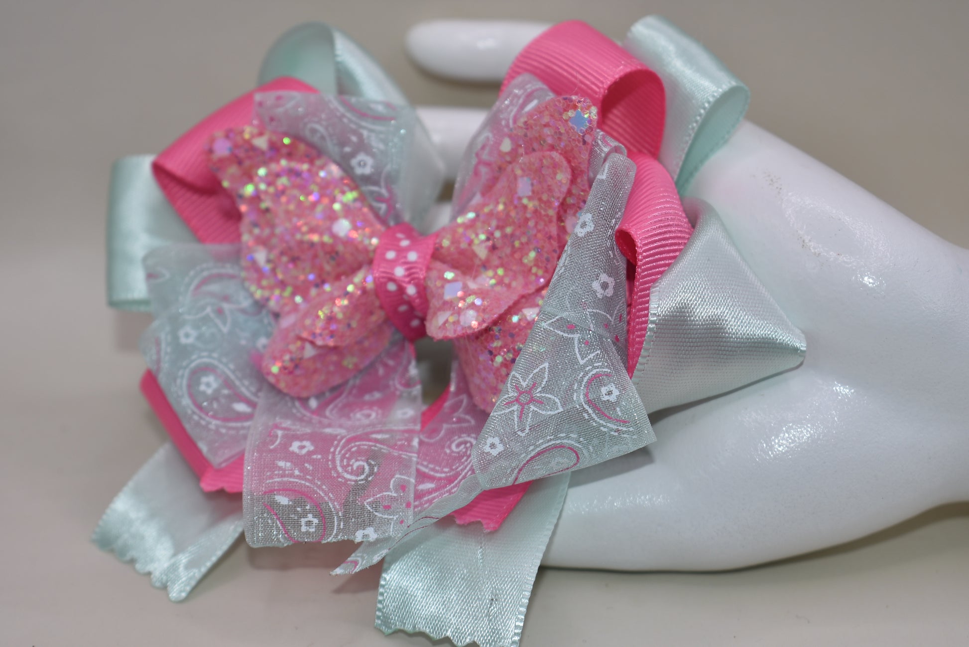 Add a touch of magic with this glittery butterfly perched atop a delicate mint green and pink ribbon. The comfy alligator clip keeps it secure, making it perfect for your little one to wear all day. Pretty, elegant, and absolutely adorable—watch her fall in love and never want to take it off! 🦋💚🎀