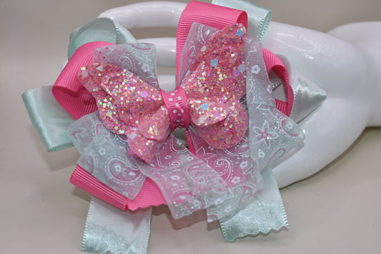 Add a touch of magic with this glittery butterfly perched atop a delicate mint green and pink ribbon. The comfy alligator clip keeps it secure, making it perfect for your little one to wear all day. Pretty, elegant, and absolutely adorable—watch her fall in love and never want to take it off! 🦋💚🎀