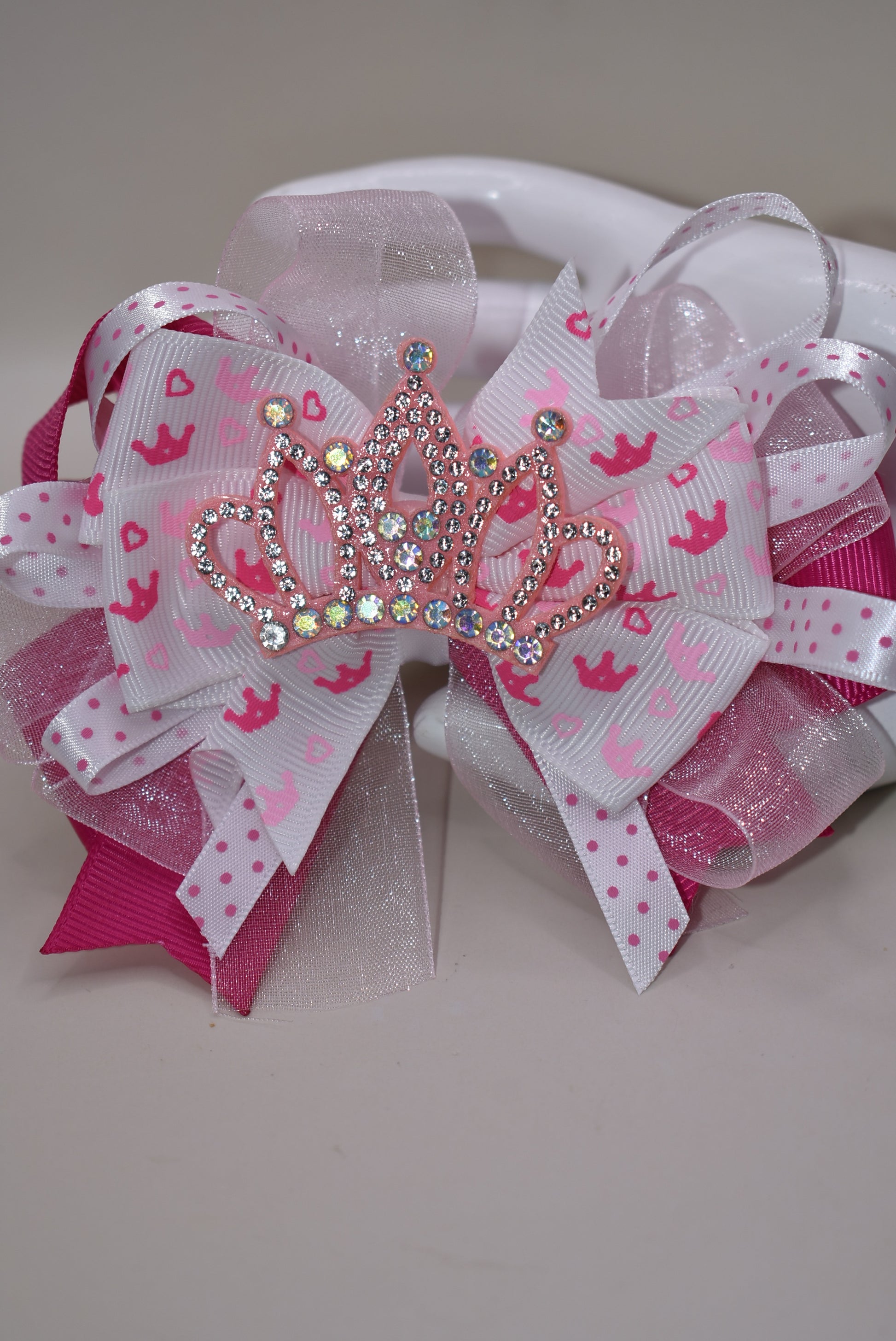 Add a touch of magic with this perfect pink princess bow! 🎀 Layers of ribbon featuring a charming princess motif come together topped with a sparkling pink glitter crown 👑. This one-of-a-kind bow clips securely with an alligator wrapped clip, making it a delightful accessory for any little princess. ✨