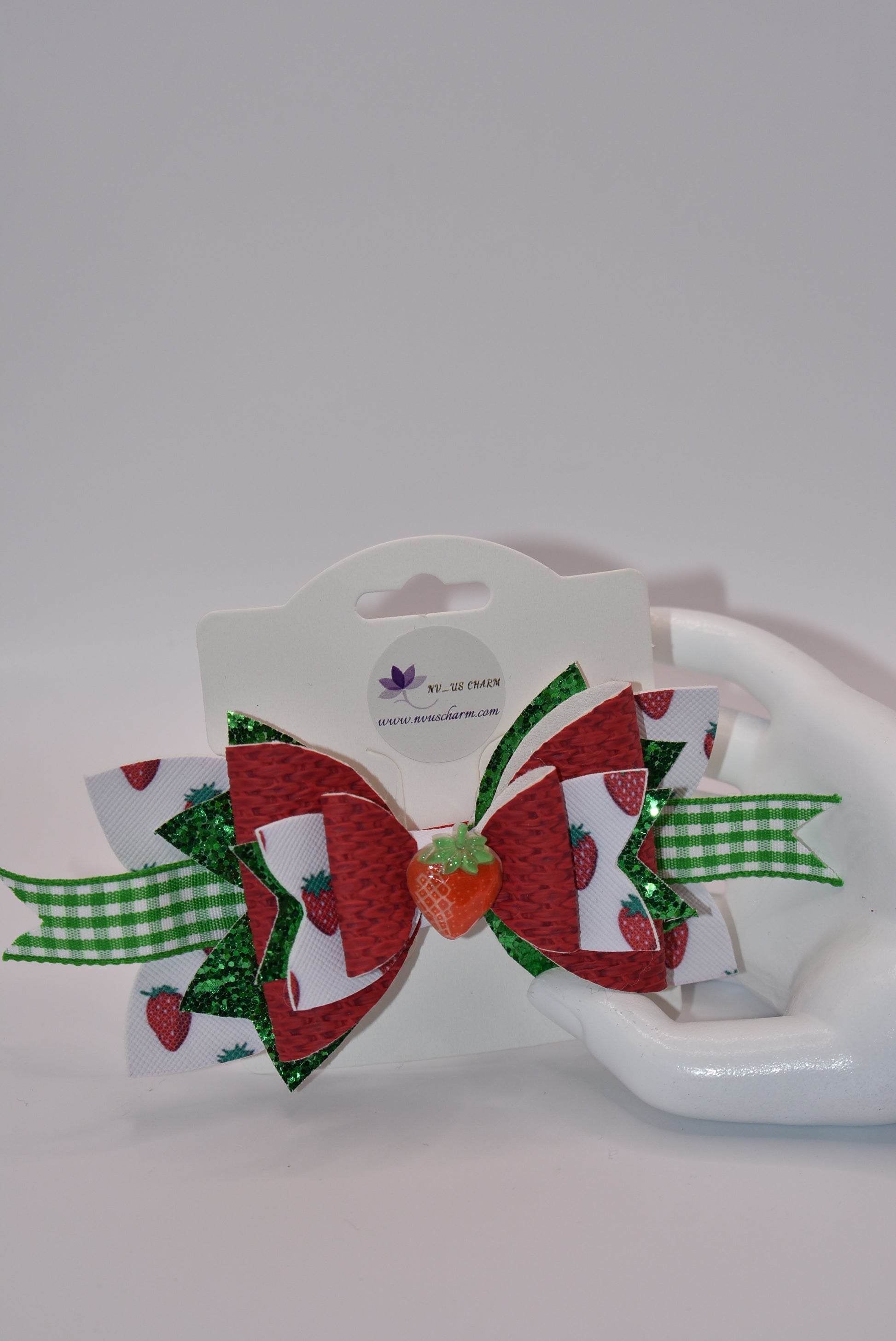 Indulge in the juicy sweetness of Nana's Collection hair clip! Made with strawberry design faux leather and a cute green and white checkered ribbon, this clip is perfect for summer with a charming strawberry charm. Plus, the alligator clip makes it easy to put in and take out of your little one's hair.