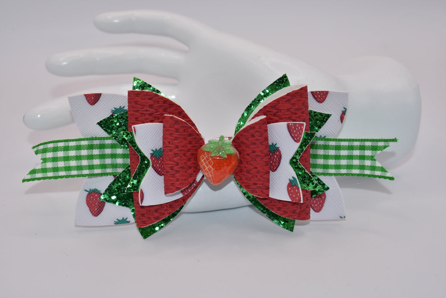 Indulge in the juicy sweetness of Nana's Collection hair clip! Made with strawberry design faux leather and a cute green and white checkered ribbon, this clip is perfect for summer with a charming strawberry charm. Plus, the alligator clip makes it easy to put in and take out of your little one's hair.