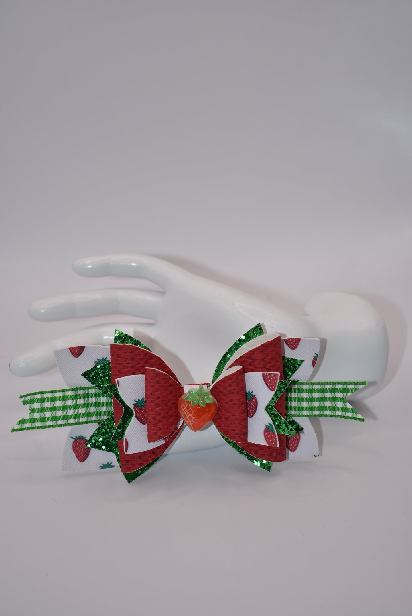 Indulge in the juicy sweetness of Nana's Collection hair clip! Made with strawberry design faux leather and a cute green and white checkered ribbon, this clip is perfect for summer with a charming strawberry charm. Plus, the alligator clip makes it easy to put in and take out of your little one's hair.