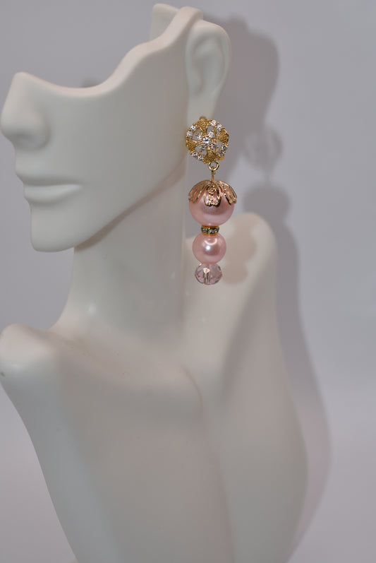 Shake up your accessory game with our Orange Collection! These prettiest peachy colored earrings feature a stunning combination of peach pearls, pink crystals, and gold accents. The secure gold crystal post with flip up clasp ensures they stay in place while you turn heads. This is a one-of-a-kind piece!