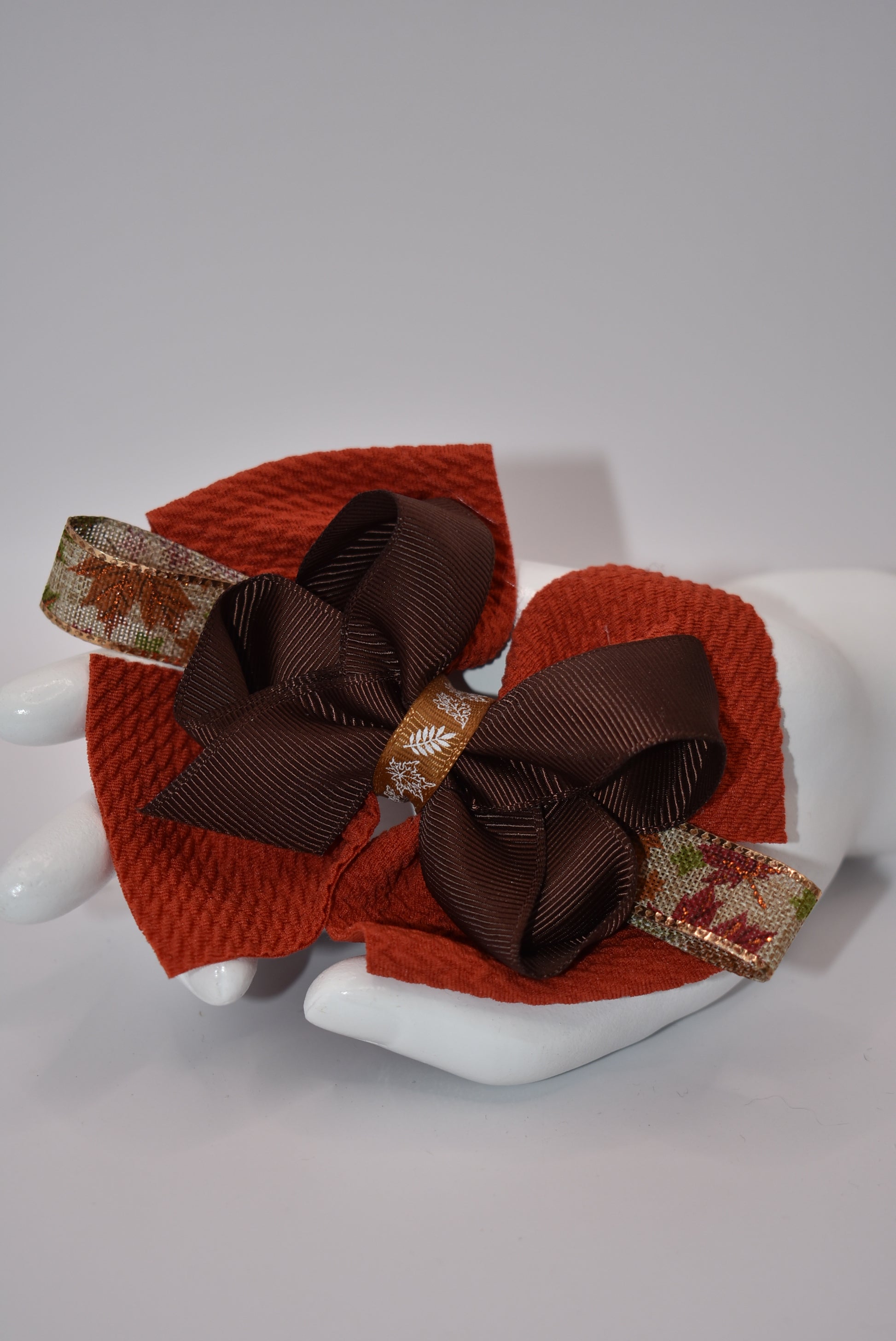 Step into fall fashion with Nana's Collection! This perfect bow features layers of pretty brown tones, accented with a leaf motif for a one-of-a-kind piece. With an alligator clip for a secure fit, this bow is both stylish and practical.