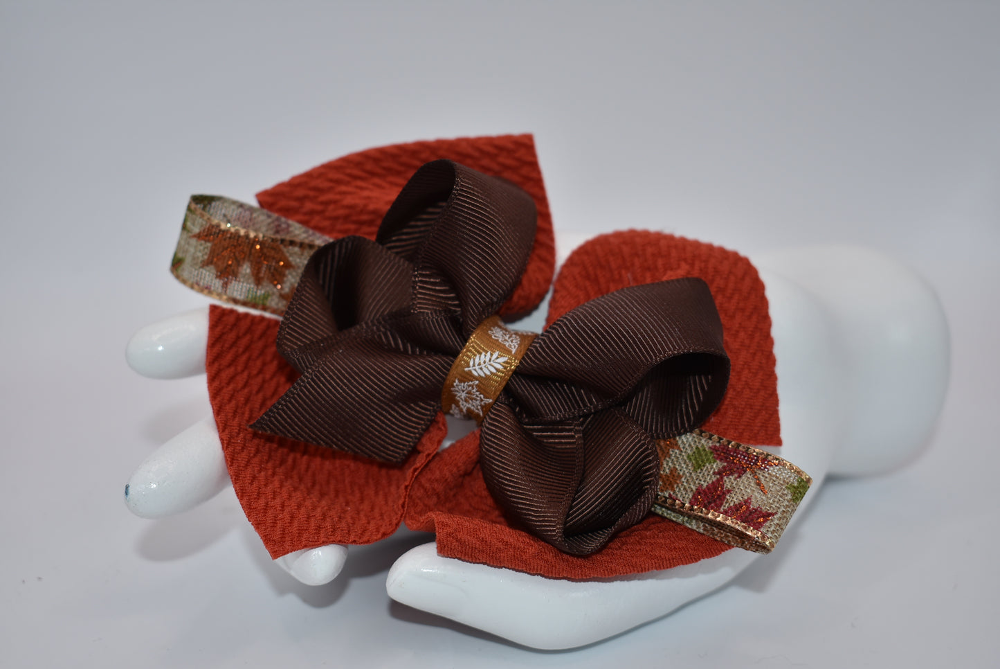 Step into fall fashion with Nana's Collection! This perfect bow features layers of pretty brown tones, accented with a leaf motif for a one-of-a-kind piece. With an alligator clip for a secure fit, this bow is both stylish and practical.