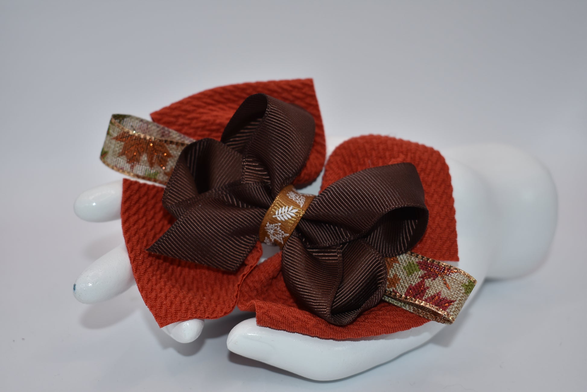 Step into fall fashion with Nana's Collection! This perfect bow features layers of pretty brown tones, accented with a leaf motif for a one-of-a-kind piece. With an alligator clip for a secure fit, this bow is both stylish and practical.