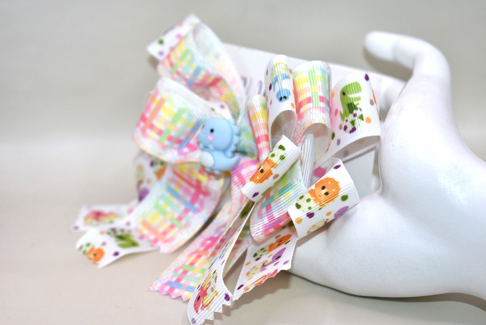 Get ready for a roar-some time with Nana's Collection 177! 🦕 This adorable dinosaur bow features layers and layers of fun dinosaur ribbon, topped with the cutest little blue dino you’ll ever see. 🦖 Secure and comfy, it clips on with a wrapped alligator clip — perfect for playtime adventures or adding a whimsical touch to any outfit! 🎀🦕