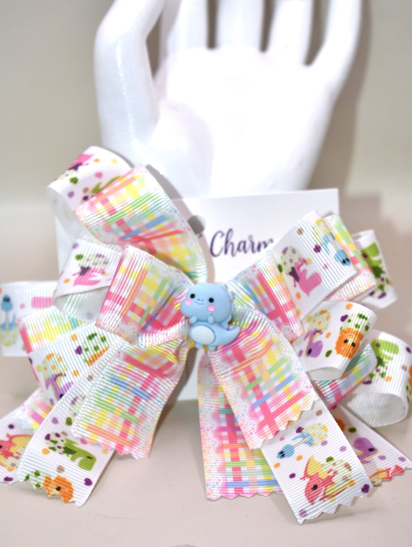 Get ready for a roar-some time with Nana's Collection 177! 🦕 This adorable dinosaur bow features layers and layers of fun dinosaur ribbon, topped with the cutest little blue dino you’ll ever see. 🦖 Secure and comfy, it clips on with a wrapped alligator clip — perfect for playtime adventures or adding a whimsical touch to any outfit! 🎀🦕