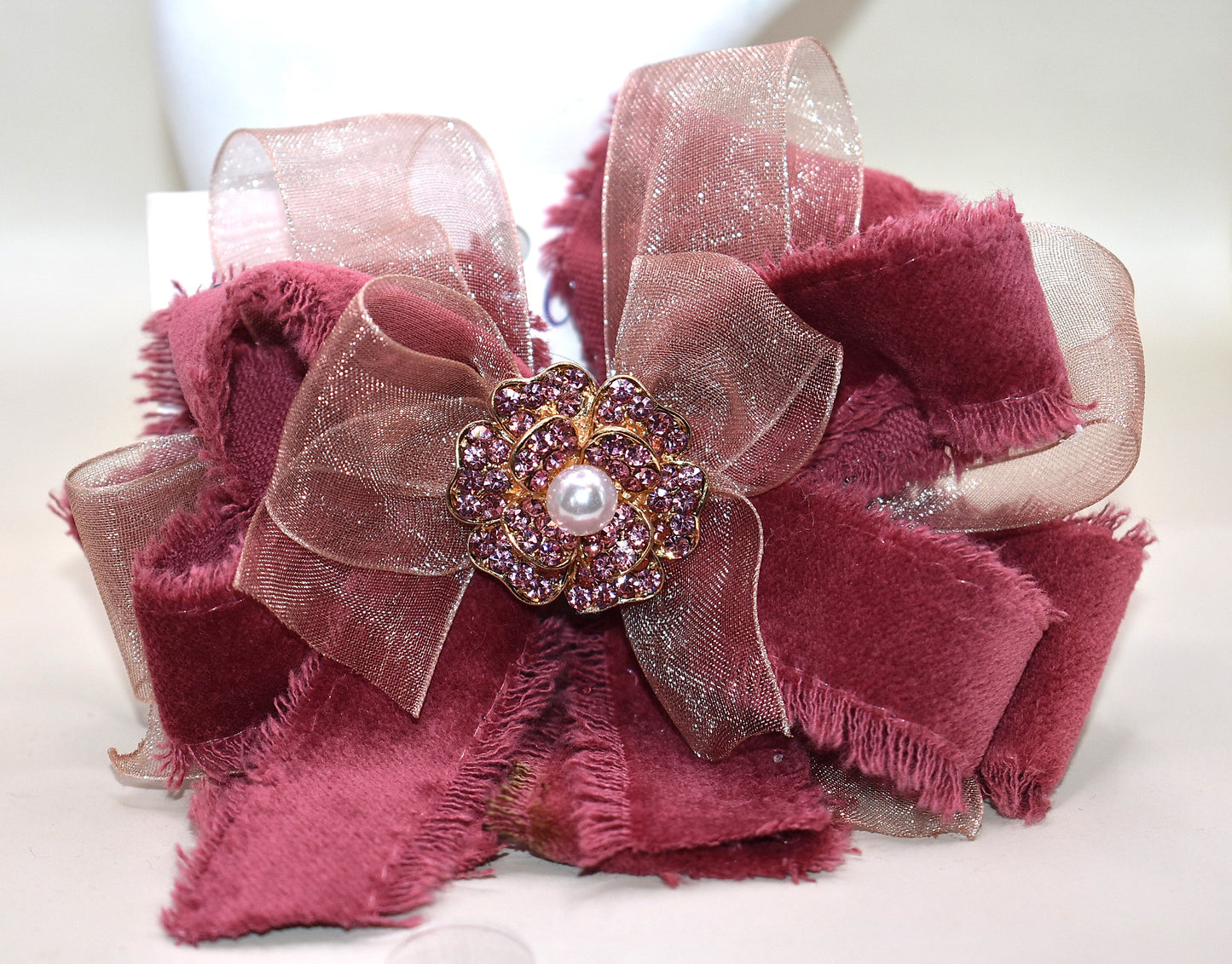 Add a playful pop of color with this gorgeous burgundy velour ribbon accented by soft pink organza. Perfect for dressing up a special outfit for you or your little one, it features a wrapped alligator clip for secure, all-day wear. A sparkling pink rhinestone and pearl piece crowns the top, tying the whole look together with charming sparkle.