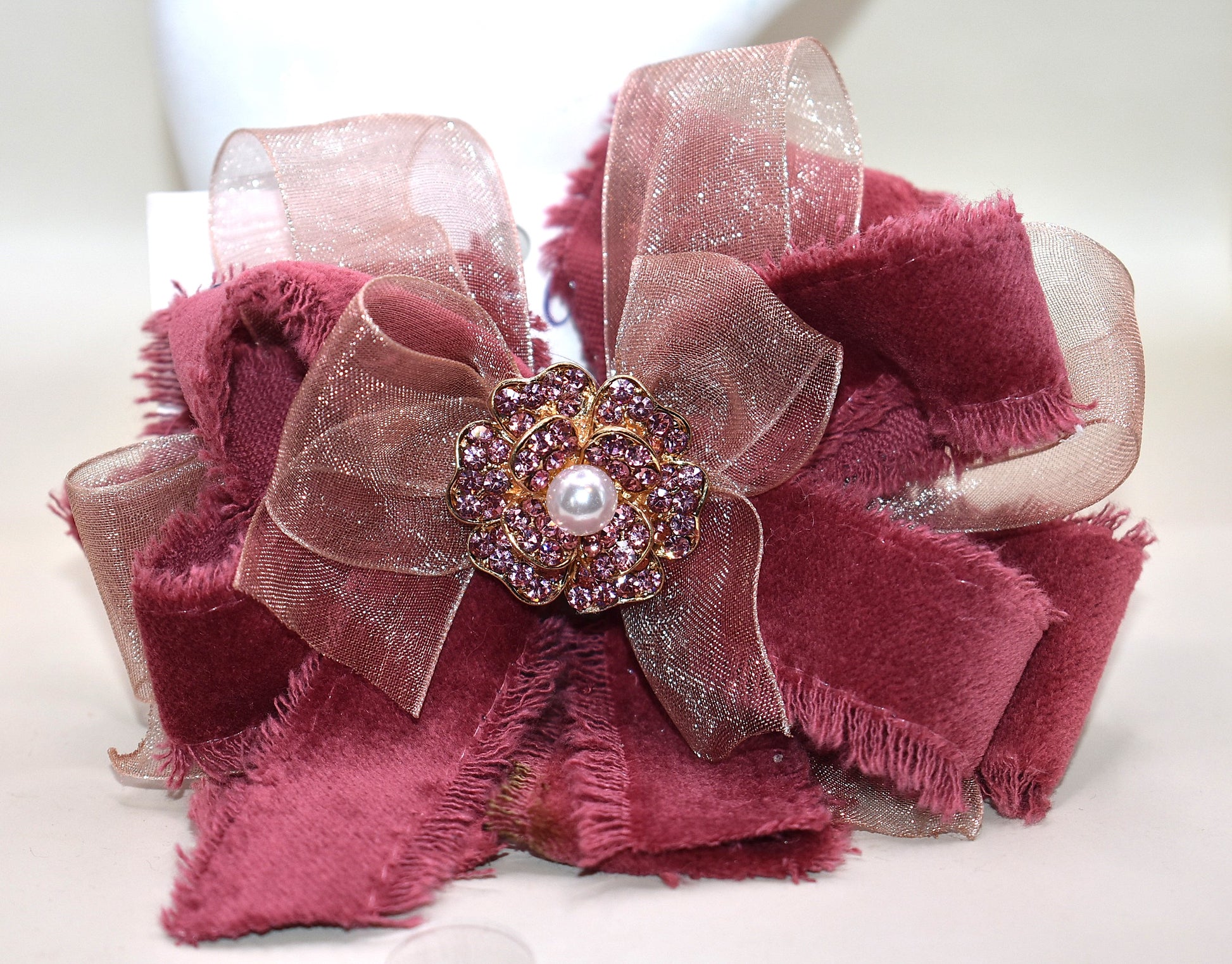 Add a playful pop of color with this gorgeous burgundy velour ribbon accented by soft pink organza. Perfect for dressing up a special outfit for you or your little one, it features a wrapped alligator clip for secure, all-day wear. A sparkling pink rhinestone and pearl piece crowns the top, tying the whole look together with charming sparkle.