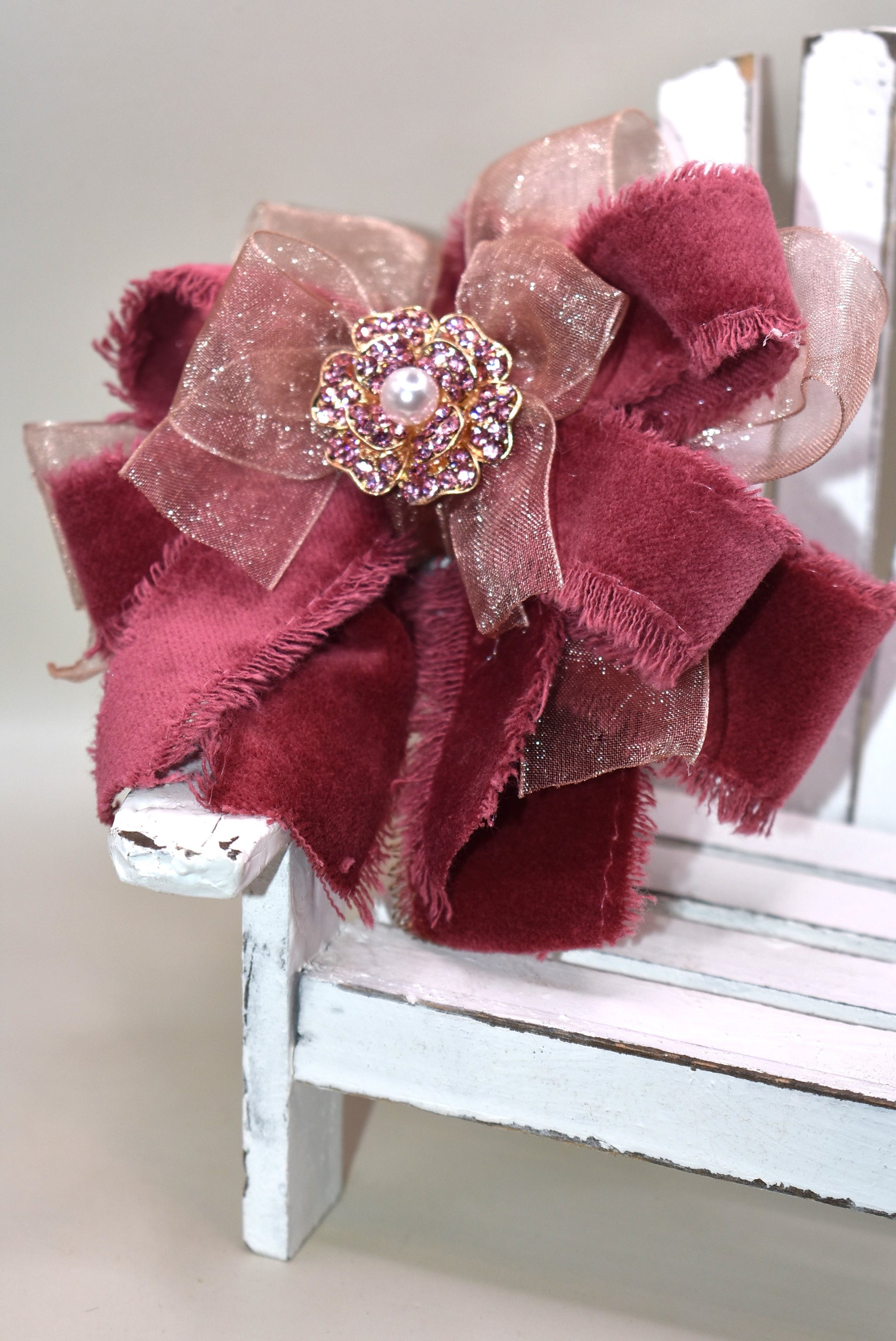 Add a playful pop of color with this gorgeous burgundy velour ribbon accented by soft pink organza. Perfect for dressing up a special outfit for you or your little one, it features a wrapped alligator clip for secure, all-day wear. A sparkling pink rhinestone and pearl piece crowns the top, tying the whole look together with charming sparkle.