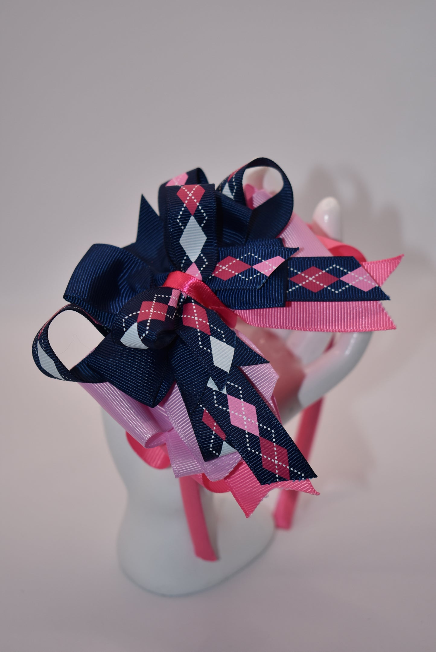 Elevate your style with Nana's Headband Collection! The cool blue, pink and white color combination is perfect for any outfit. The pretty pink satin-wrapped headband adds a touch of elegance, while the layers of quality ribbon give it a unique charm. Say goodbye to boring hair days with this playful and stylish accessory.