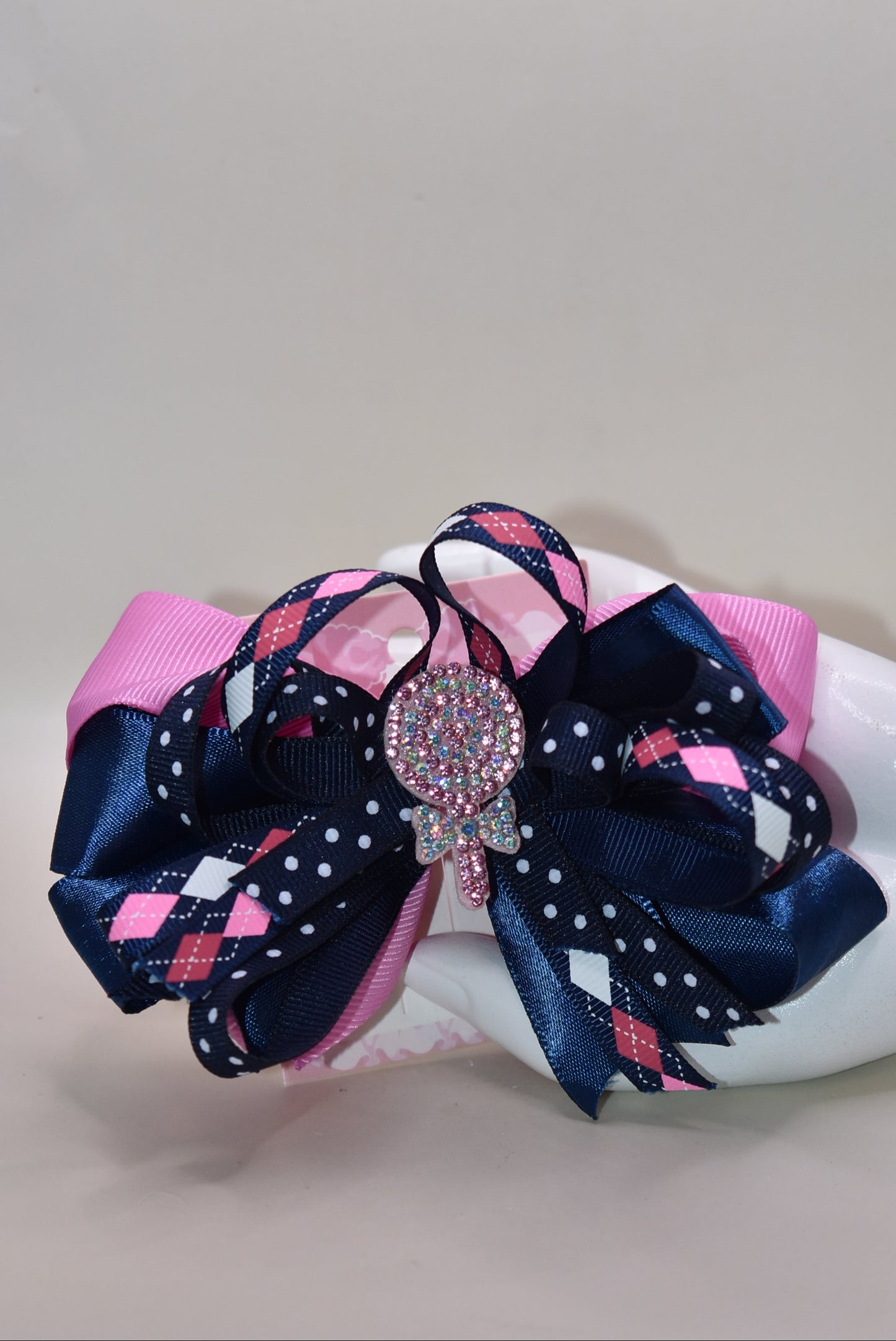 Add a pop of fun with this playful bow from Nana's Collection! Layers of pretty blue and pink ribbons create a charming swirl topped with a sparkling candy embellishment that’s sure to catch the eye 🍬✨. Perfect for adding a little extra sparkle to any outfit, it stays put all day thanks to a handy wrapped alligator clip. Sweet style made easy! 🎀