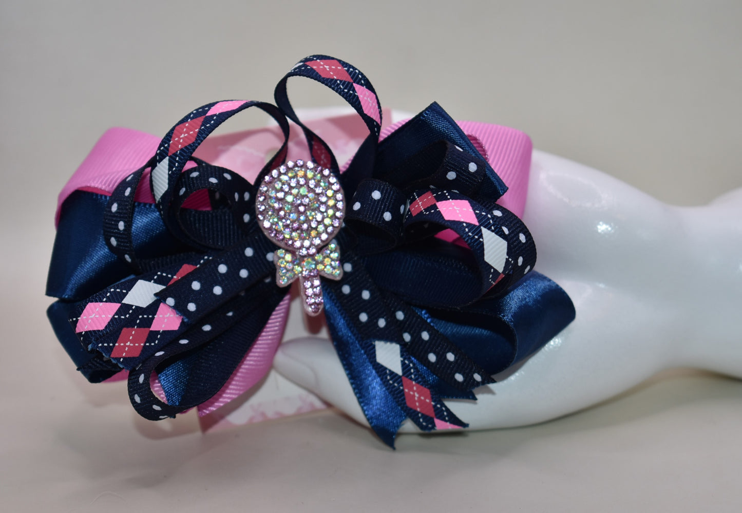Add a pop of fun with this playful bow from Nana's Collection! Layers of pretty blue and pink ribbons create a charming swirl topped with a sparkling candy embellishment that’s sure to catch the eye 🍬✨. Perfect for adding a little extra sparkle to any outfit, it stays put all day thanks to a handy wrapped alligator clip. Sweet style made easy! 🎀