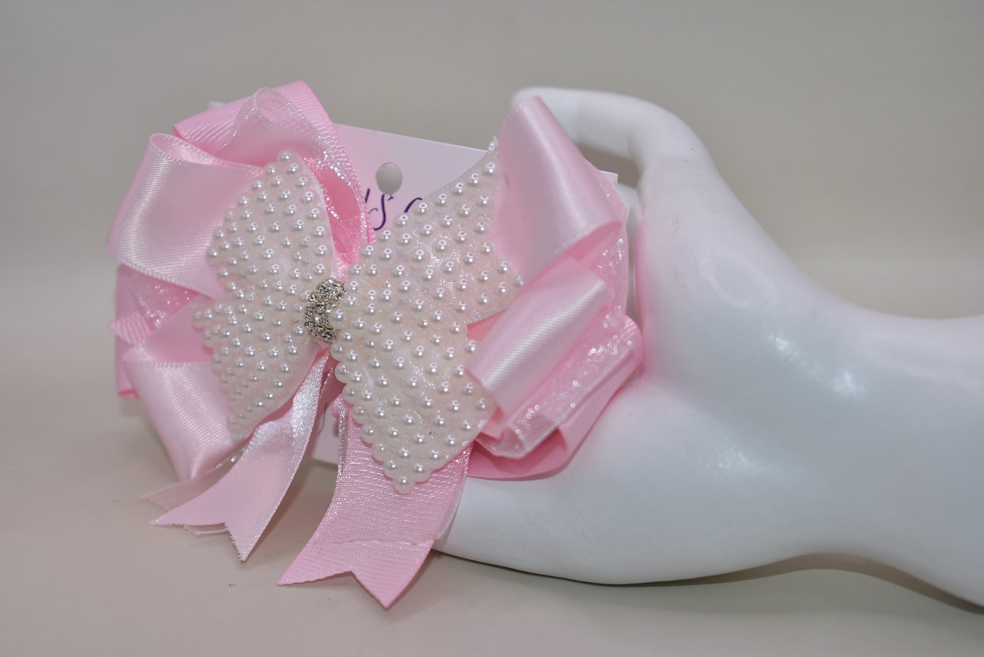 Add a splash of charm with this beautiful pink bow from Nana's Collection! 🌸 Layers of soft pink ribbons create a perfect princess look, topped with a sparkling pearl and crystal wrap ✨. The wrapped alligator clip makes it super easy to wear all day long. Perfect for the little girl who loves everything pink and pretty! 🎀💕
