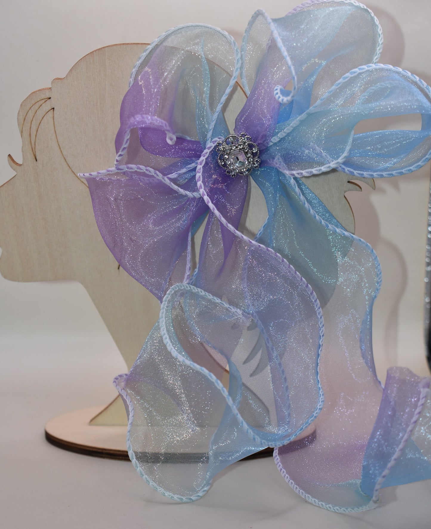 Elevate your style with this exquisite purple and blue sheer bow featuring a graceful fishtail edge. Long and elegant, it effortlessly adds a refined touch to any outfit. Secured with a wrapped alligator clip for easy wear, it is adorned with a delicate silver gem charm that completes its sophisticated appeal.