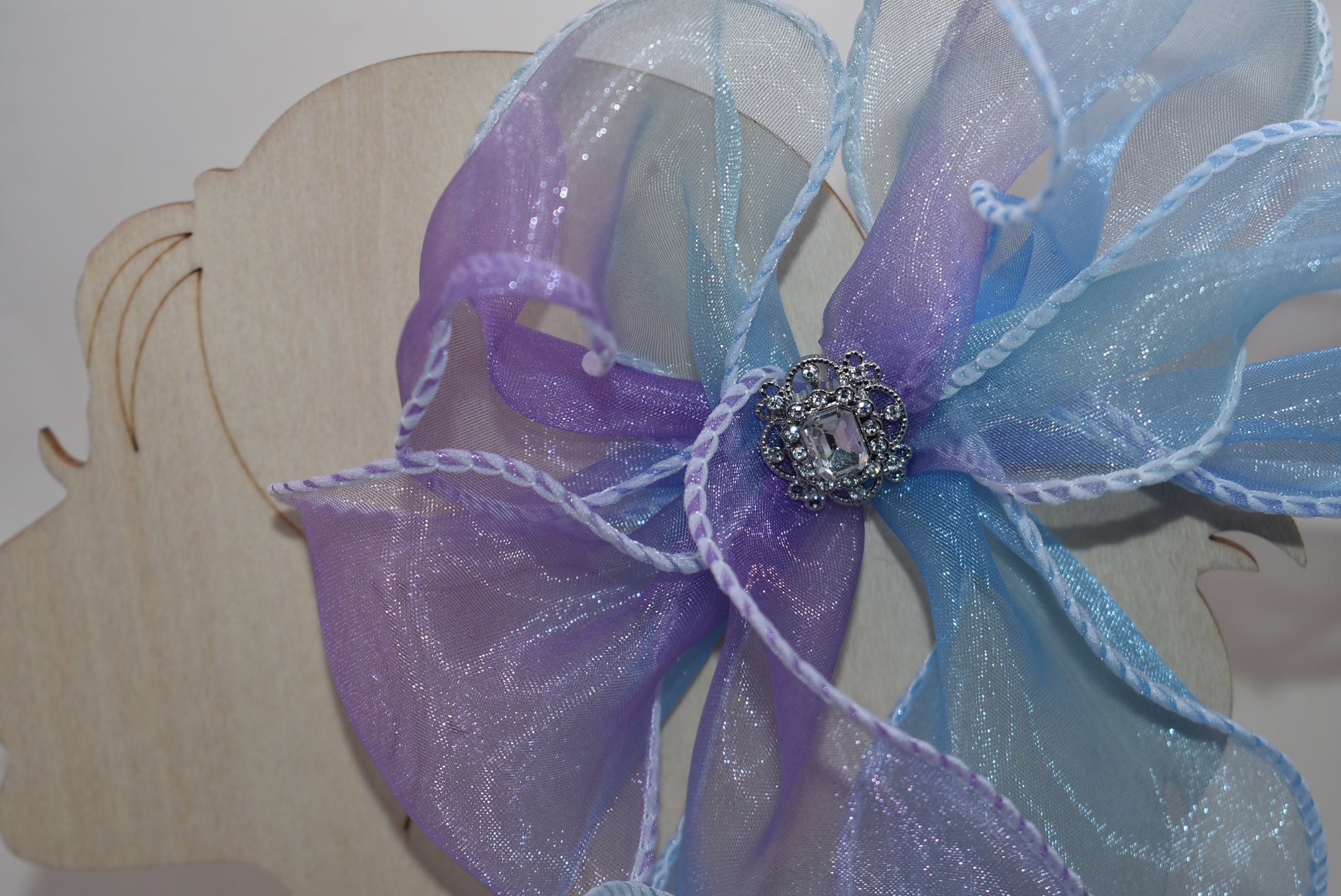 Elevate your style with this exquisite purple and blue sheer bow featuring a graceful fishtail edge. Long and elegant, it effortlessly adds a refined touch to any outfit. Secured with a wrapped alligator clip for easy wear, it is adorned with a delicate silver gem charm that completes its sophisticated appeal.