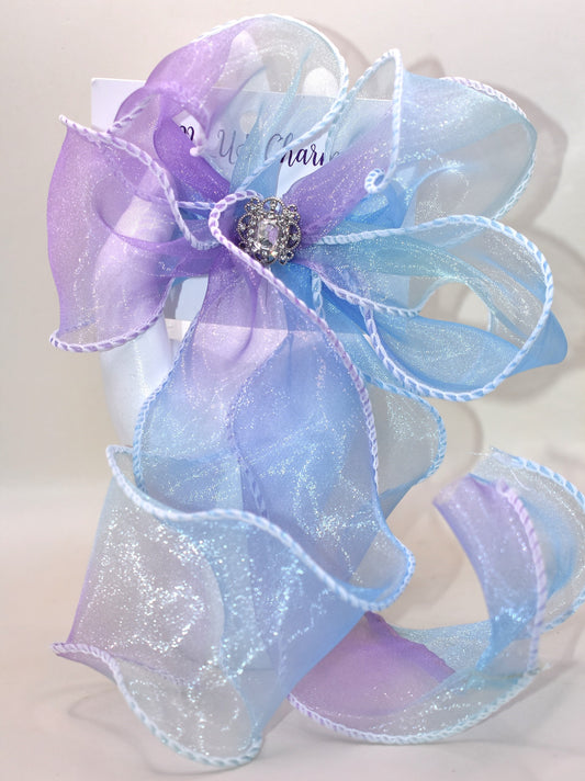 Elevate your style with this exquisite purple and blue sheer bow featuring a graceful fishtail edge. Long and elegant, it effortlessly adds a refined touch to any outfit. Secured with a wrapped alligator clip for easy wear, it is adorned with a delicate silver gem charm that completes its sophisticated appeal.