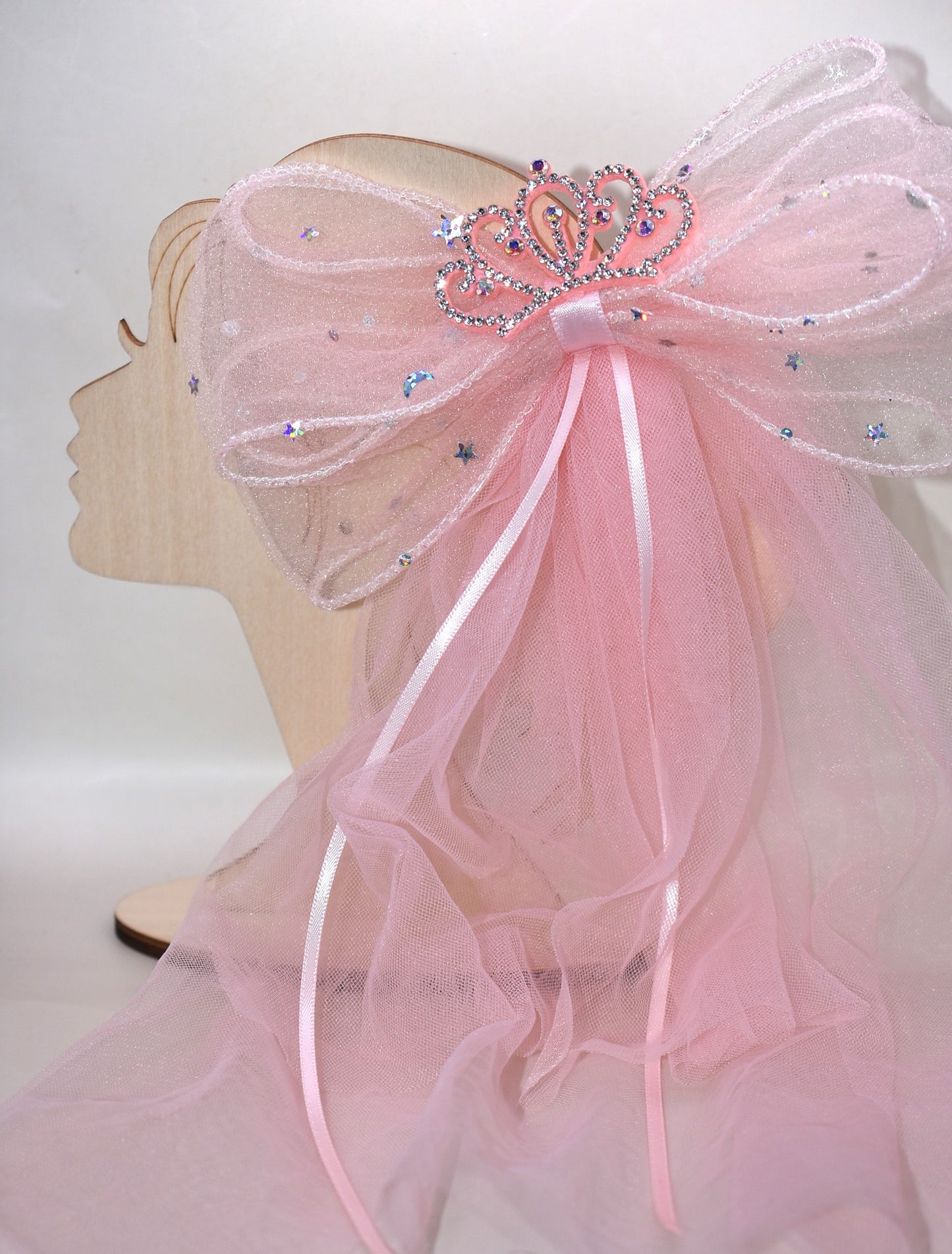 Add a touch of royalty with the Long Tail Collection 6 bow. Featuring a charming crown jewel perched atop layers of soft, flowing tulle, this easy clip-on accessory is perfect for anyone dreaming of a princess-worthy look. Effortlessly elevate any outfit with a playful sparkle that delights both kids and adults alike.